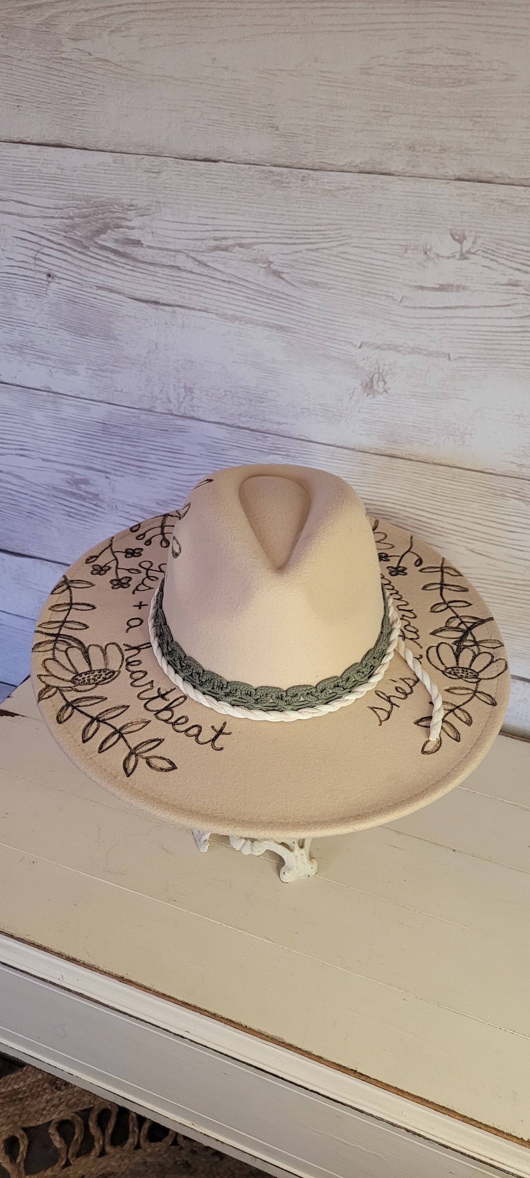 Custom engraved by Kayla Features whimsical flowers Ivory brim hat fedora style Felt hat Flat brim 65% polyester and 35% cotton Ribbon drawstring for hat size adjustment Head Circumference: 25" H:5.25" L:16" W:14.5"