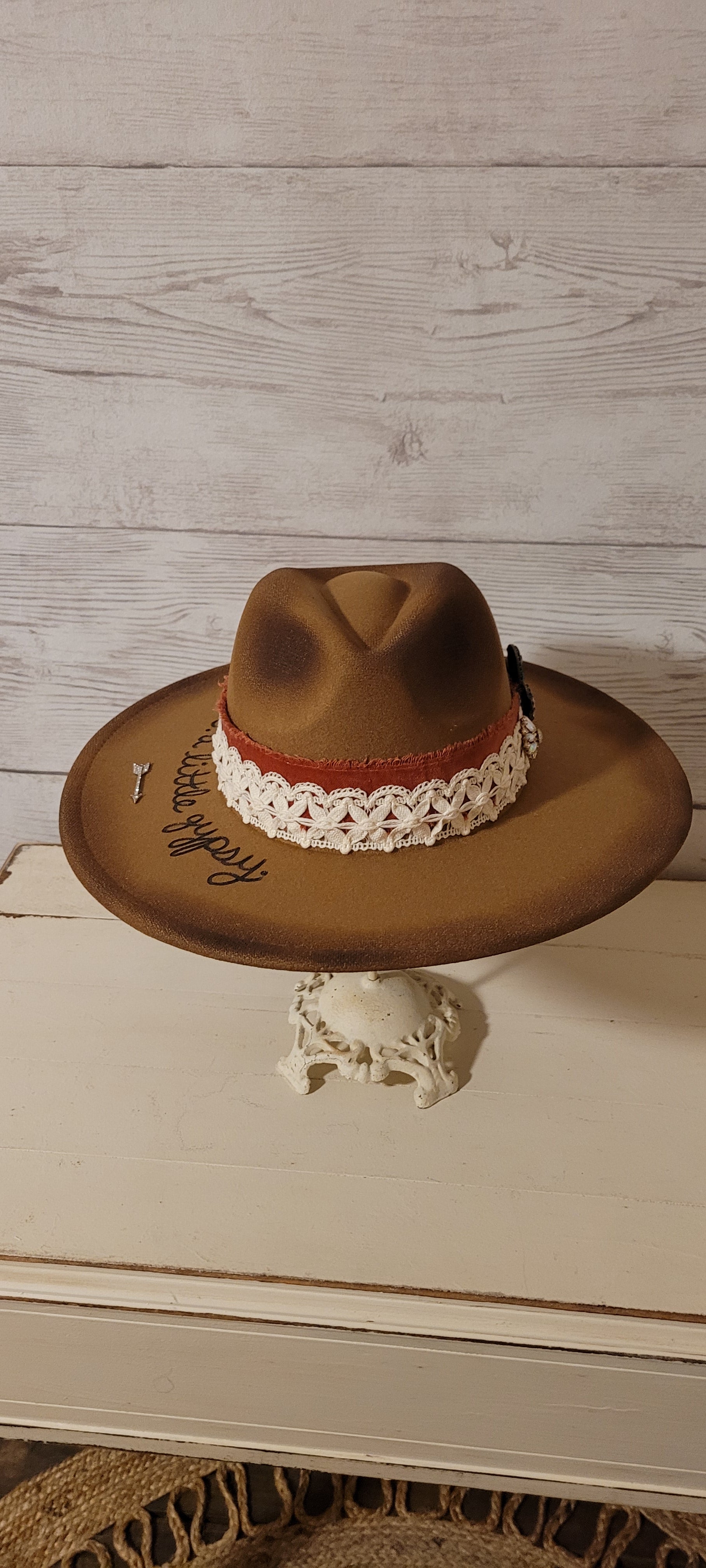 Features "a little hippie. a little gypsy." Natural lace ribbon, frayed velvet ribbon, rhinestone brooches: AB flowers, cactus & arrow Felt hat Flat brim 90% polyester & 10% PU Ribbon drawstring for hat size adjustment Head Circumference: 24" Crown Height: 5" Brim Length: 15.75" Brim Width: 14.5" Branded & numbered inside crown Custom burned & engraved by Kayla