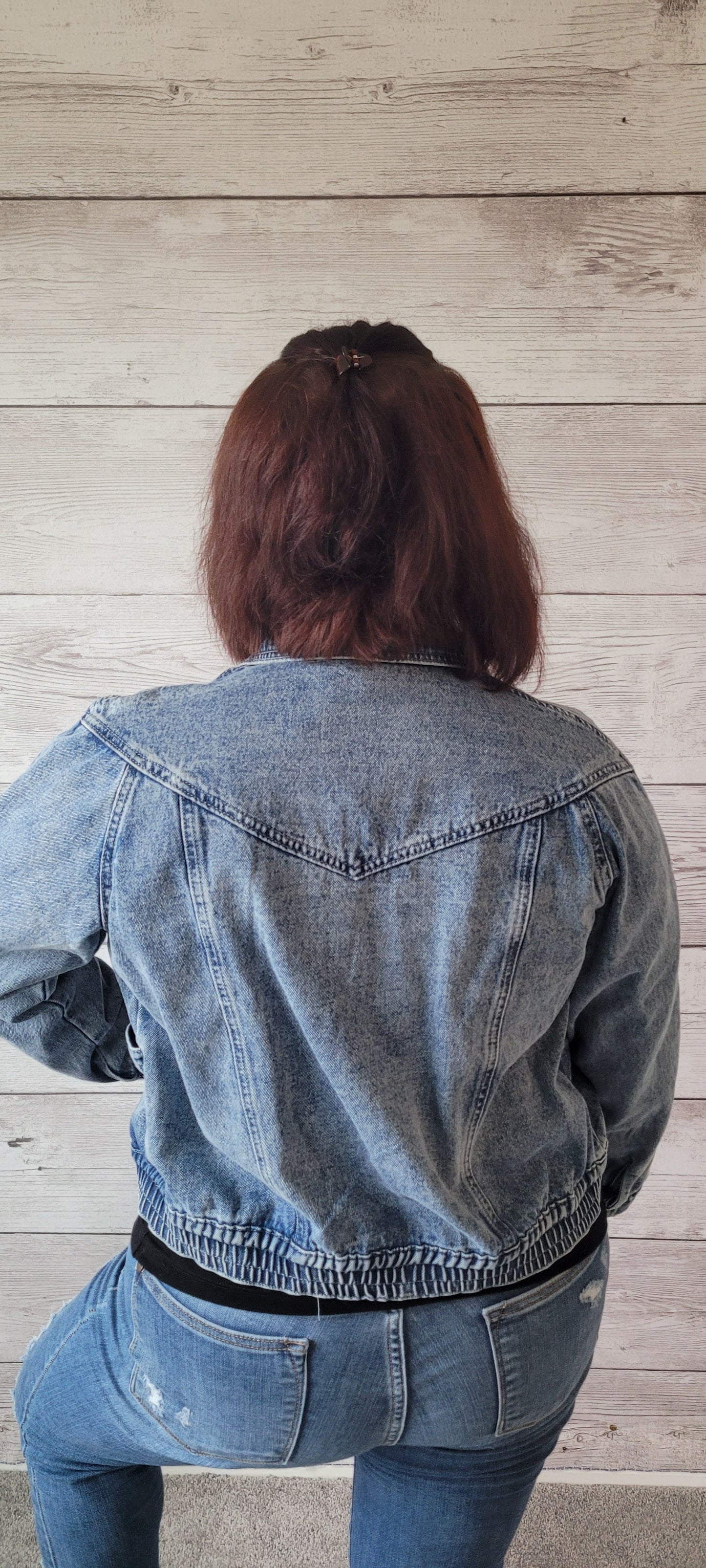 For a look that's as chill as you are, reach for this denim bomber jacket! Its distressed wash makes a stylish statement, while its elastic waistband and functional snap pockets ensure maximum comfiness. Instantly elevate any outfit with this bomber's zip up, collar neckline, slightly cropped silhouette, and asymmetrical closure with snaps down front. Don't be surprised if you end up wearing this fly little number every single day! Sizes small through large.