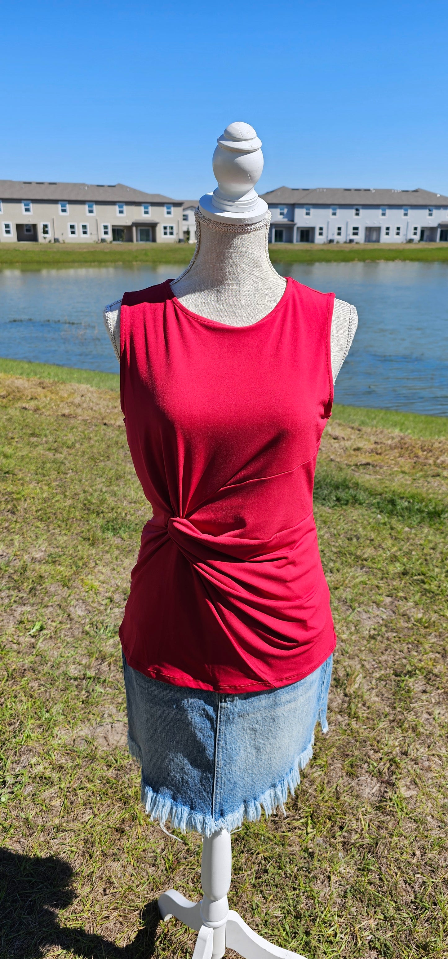 This is a perfect basic staple piece! It is a great piece for layering or great all by itself! This is a sleeveless round neck top, with a knot in front which gives it a gathered layered look, and straight line hem. The color is red. Pair with your favorite pair of denim jeans, shorts, or skirt. Sizes small through x-large.