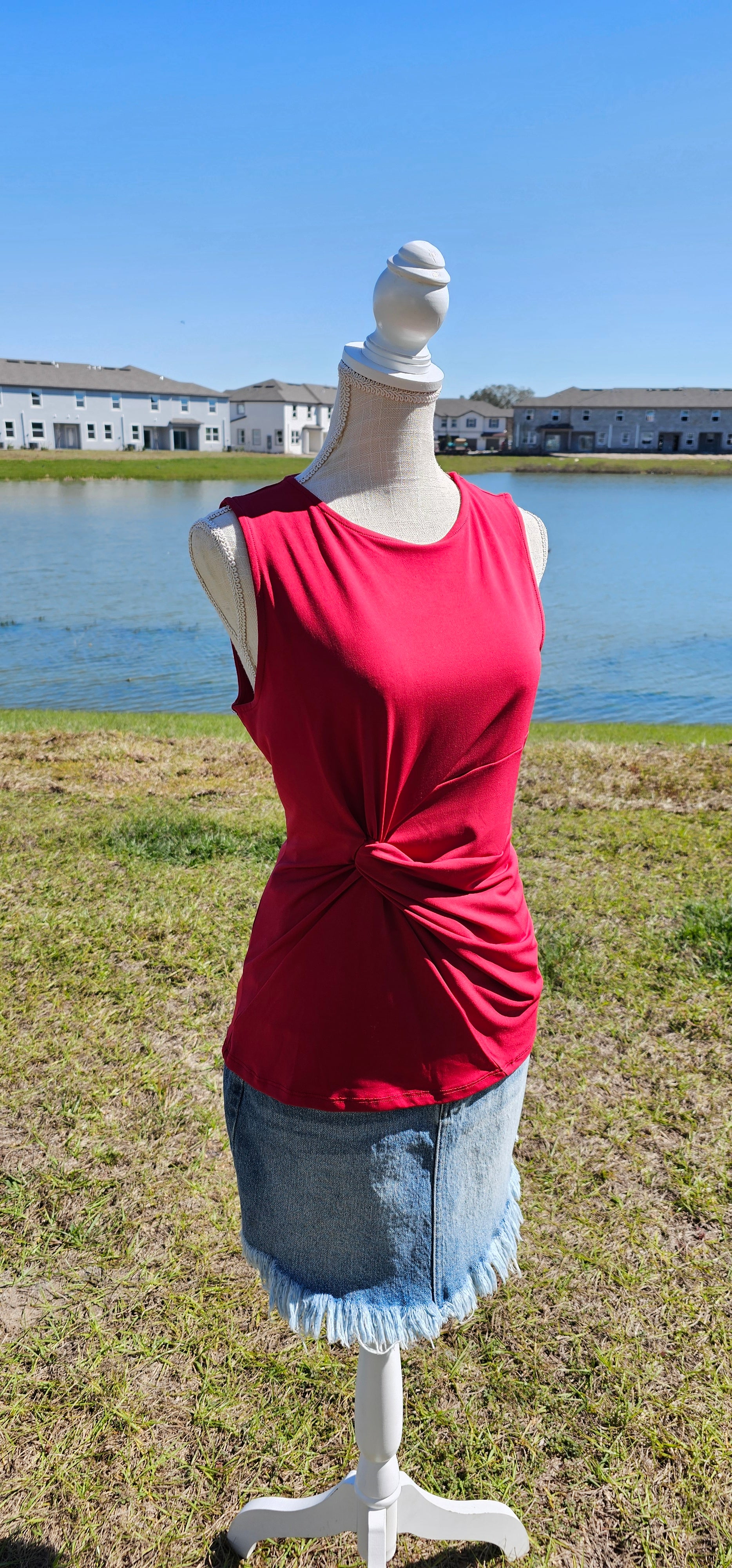 This is a perfect basic staple piece! It is a great piece for layering or great all by itself! This is a sleeveless round neck top, with a knot in front which gives it a gathered layered look, and straight line hem. The color is red. Pair with your favorite pair of denim jeans, shorts, or skirt. Sizes small through x-large.