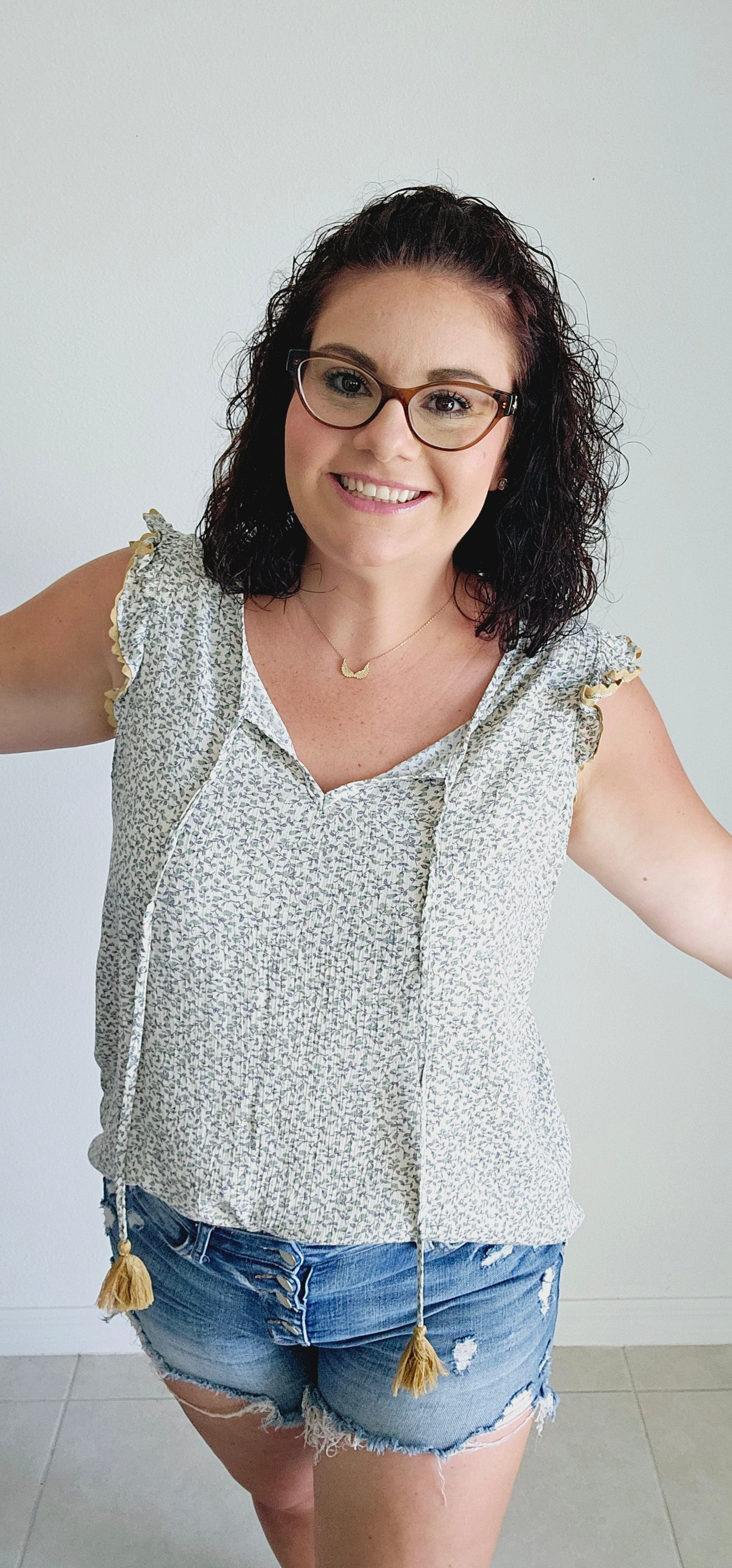 This fun and flirty blouse features a playful ditsy floral pattern and charming scalloped mustard trim. The ruffle sleeves add a touch of whimsy, while the tie closure with mustard tassels offers a unique and stylish detail. Perfect for a quirky and playful look. Sizes small through large.