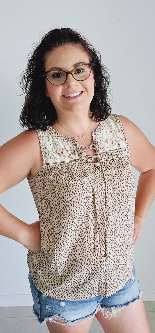 Unleash your wild side in this sleeveless top! This fierce top features a playful leopard print and a delicate lace yoke for a touch of elegance. With a sexy lace-up v-neck, you'll be turning heads wherever you go. Roar with style in beige! Sizes small through large.