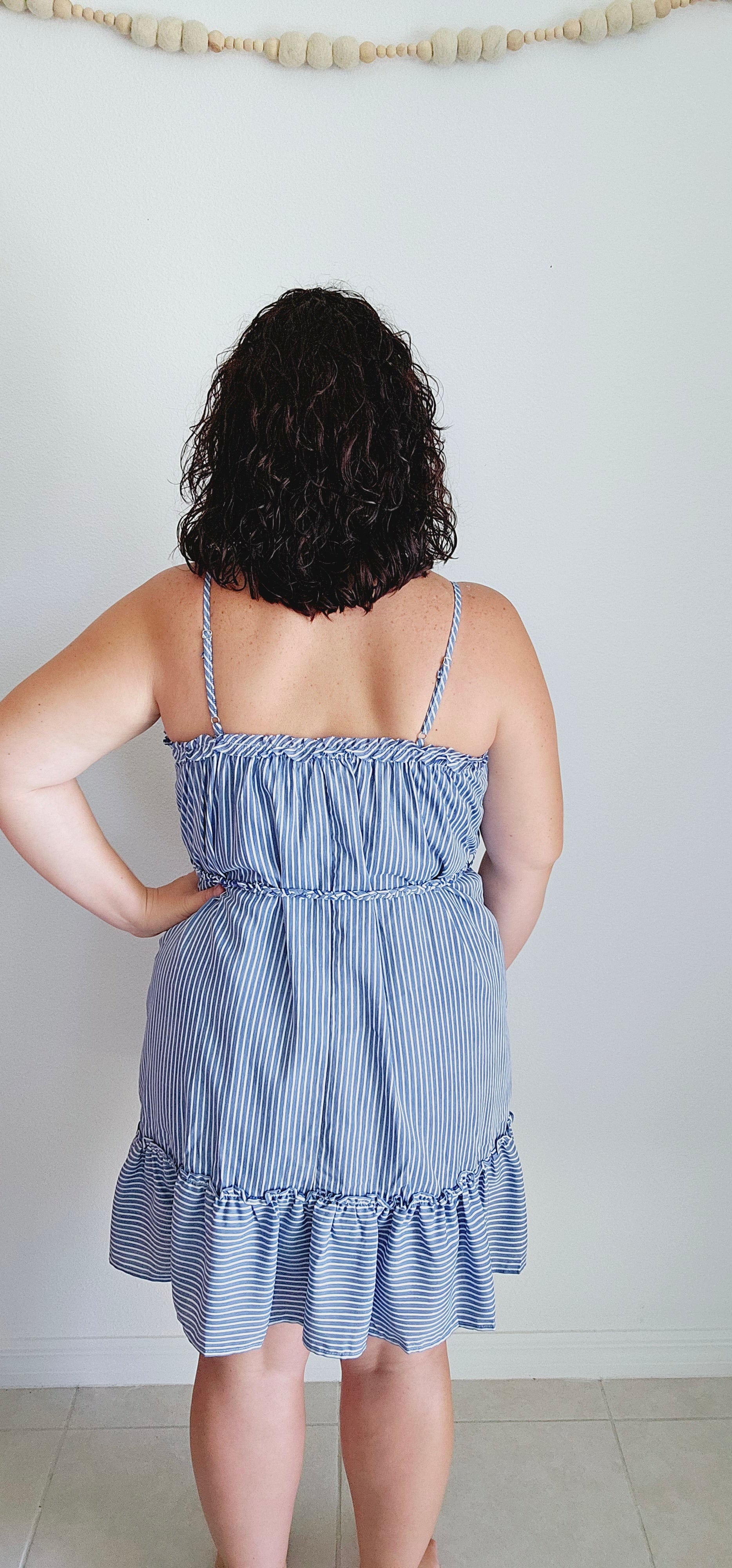 Get ready for some serious beach vibes with this gorgeous dress. This dress features a playful ruffle trim and hem, adjustable spaghetti straps for the perfect fit, and a braided belt for a touch of uniqueness. The vertical royal blue and white stripes will have you feeling like a seaside goddess. Sizes small through large.