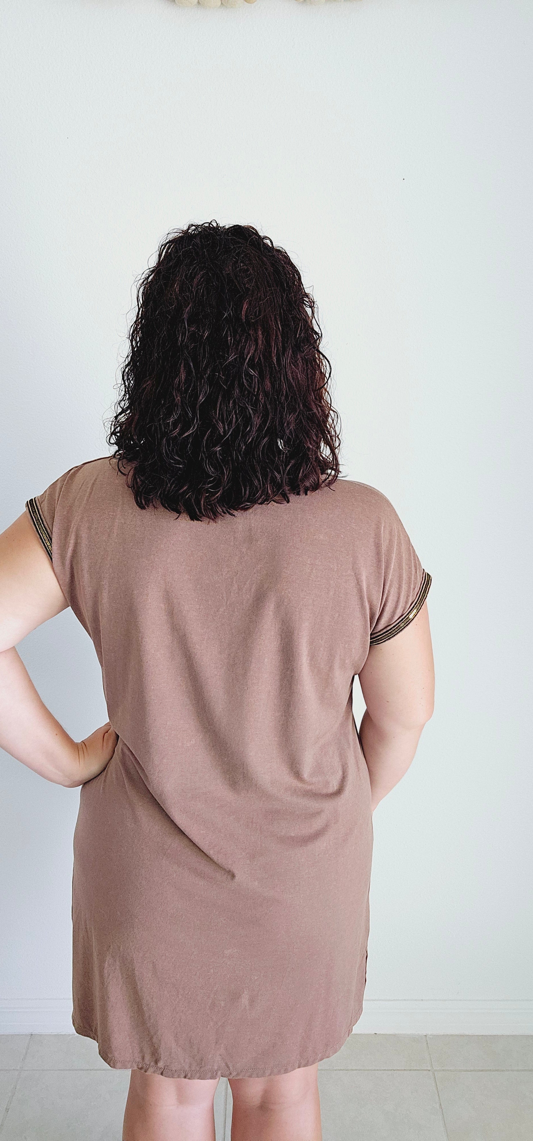 This T-shirt dress boasts an edgy washed effect and eye-catching bead trim for a unique and playful look. Perfect for any casual occasion, you'll be sure to turn heads and have fun in this mocha dress. Sizes small through large.