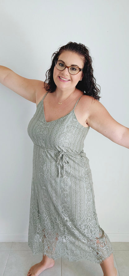 This A-line slip dress features a delicate lace overlay and a flattering waist tie, perfect for accentuating your figure. With adjustable shoulder straps and a soft rayon lining, this dress is both stylish and comfortable. Wear it to your next event for a touch of elegance with a modern twist. Sizes small through large.