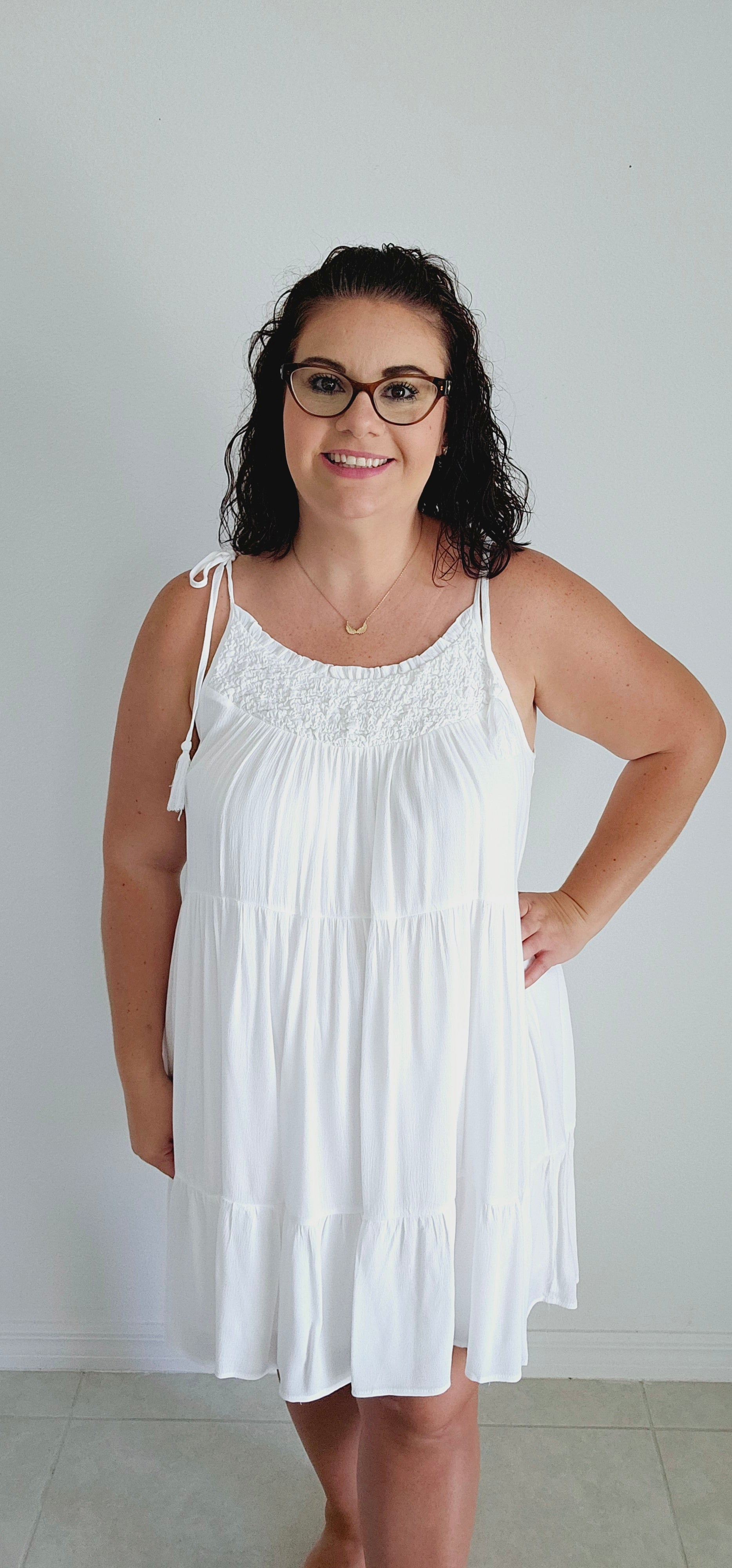 Get ready to make a statement with this flirty mini dress. Featuring a unique popcorn smocking chest and playful tassel detail straps, this dress is perfect for those vacation vibes. The tiered mini length adds a touch of fun and flirty to your look. Bring on the sun! Sizes small through large.