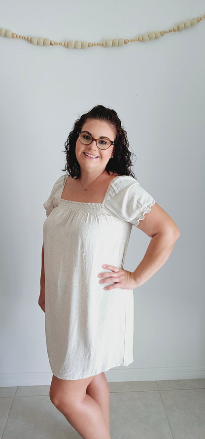 Be the queen of comfort and style in this adorable babydoll dress. With its smocked square neckline and puff short sleeves, this oatmeal-colored dress is perfect for any occasion. Its thigh length adds a flirty touch, making you feel confident and carefree. Don't miss out on this must-have dress! Sizes small through large.