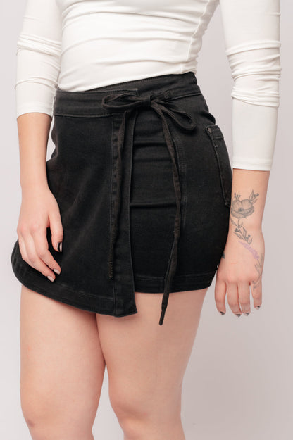 Experience elevated style with our Bentli High Rise Side Tie Denim Skort in Black. Embrace the trending skort look with this sleek and sophisticated non-distressed piece in rich black. The high rise and side tie closure create a flattering fit, making it a must-have addition to any wardrobe.&nbsp; 0-3X