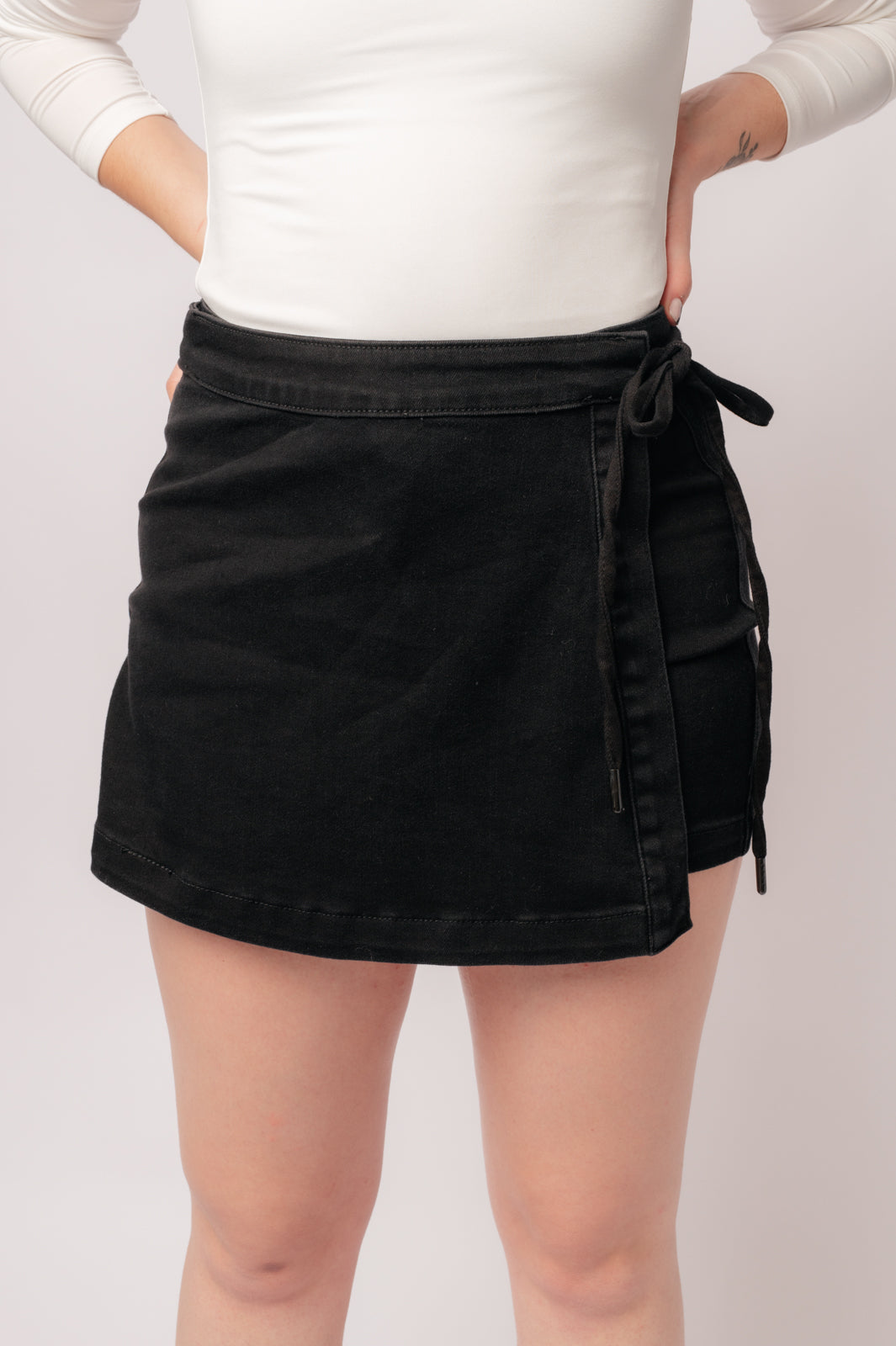 Experience elevated style with our Bentli High Rise Side Tie Denim Skort in Black. Embrace the trending skort look with this sleek and sophisticated non-distressed piece in rich black. The high rise and side tie closure create a flattering fit, making it a must-have addition to any wardrobe.&nbsp; 0-3X