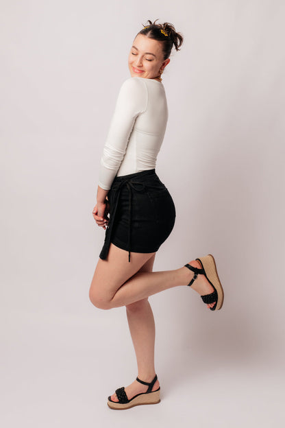 Experience elevated style with our Bentli High Rise Side Tie Denim Skort in Black. Embrace the trending skort look with this sleek and sophisticated non-distressed piece in rich black. The high rise and side tie closure create a flattering fit, making it a must-have addition to any wardrobe.&nbsp; 0-3X