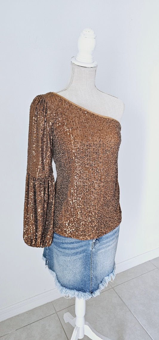 This gold sequined one shoulder top features a long puff sleeve, lining throughout, and side zipper with clasp. Pair with your favorite skirt or dress pants. Don’t be afraid to get creative! Sizes small through large.