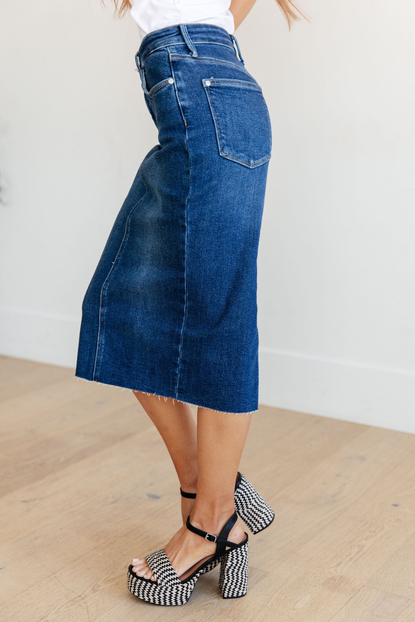 Get ready to rock your denim look with the Marcy High Rise Denim Midi Skirt from Judy Blue! With a flattering high rise fit and a versatile dark wash, this skirt is perfect for any occasion. The 4-way stretch and back vent provide a comfortable and stylish fit, while the raw hem adds a touch of edge. Say goodbye to ill-fitting skirts and hello to the perfect fit! s-3x