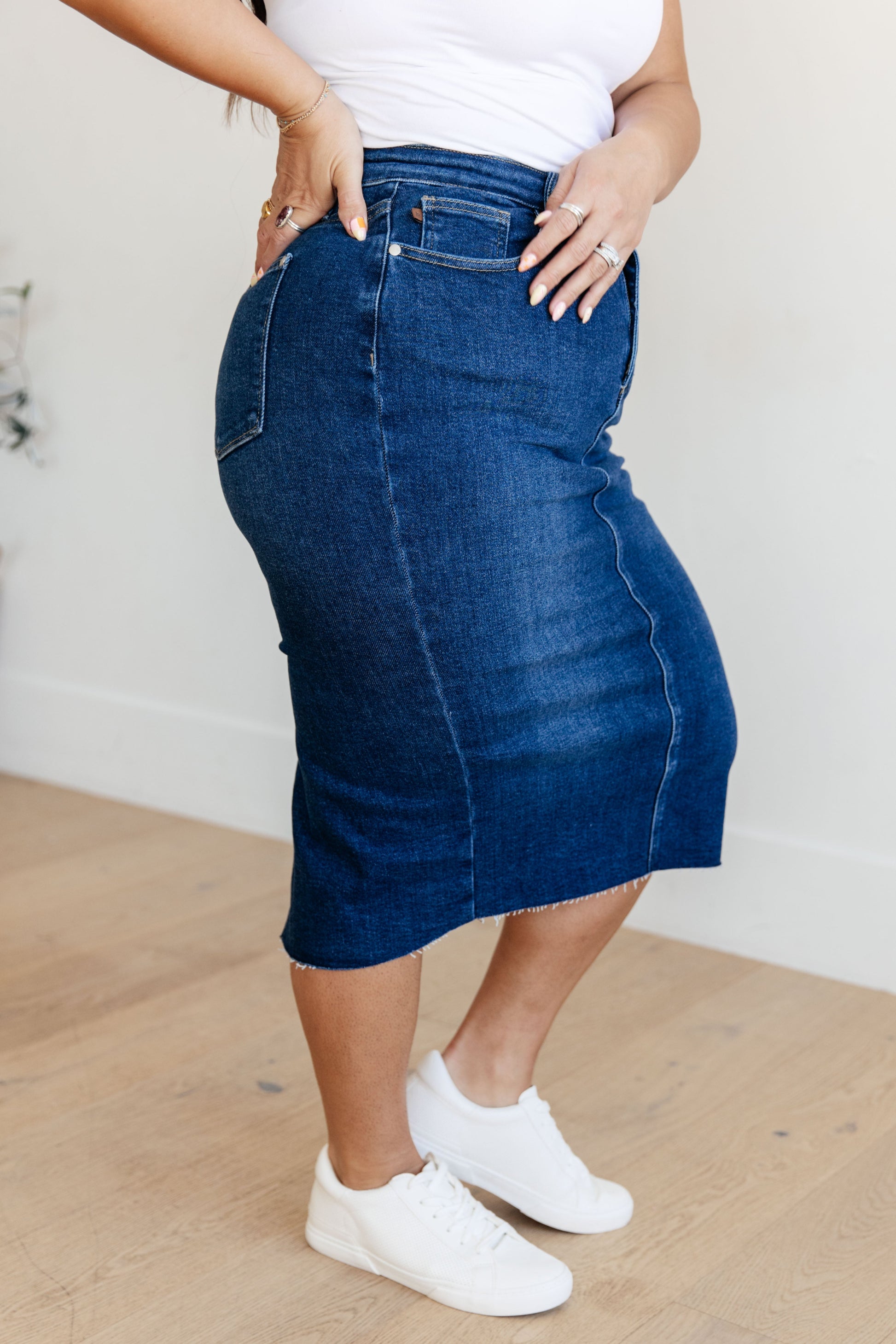 Get ready to rock your denim look with the Marcy High Rise Denim Midi Skirt from Judy Blue! With a flattering high rise fit and a versatile dark wash, this skirt is perfect for any occasion. The 4-way stretch and back vent provide a comfortable and stylish fit, while the raw hem adds a touch of edge. Say goodbye to ill-fitting skirts and hello to the perfect fit! s-3x