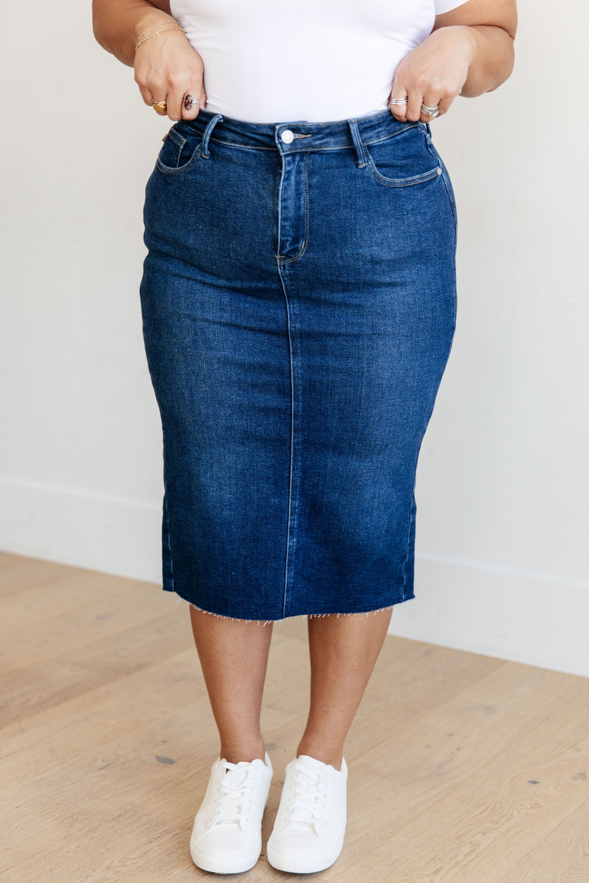 Get ready to rock your denim look with the Marcy High Rise Denim Midi Skirt from Judy Blue! With a flattering high rise fit and a versatile dark wash, this skirt is perfect for any occasion. The 4-way stretch and back vent provide a comfortable and stylish fit, while the raw hem adds a touch of edge. Say goodbye to ill-fitting skirts and hello to the perfect fit! s-3x