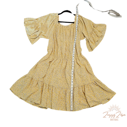 “A Ray Of Sunshine” is a dandelion color mini dress with a floral pattern (white, black, brown, green). This tiered dress features an elastic ruffle rounded neckline, ruffled sleeves, and elastic waistband. It does have a lining and two functional pockets! Imagine yourself in a field of wildflowers making wishes on dandelions. Sizes small through large.