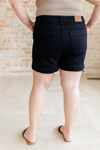 Step up your shorts game with the Reagan High Rise Button Fly Trouser Shorts from Judy Blue! These high-waisted shorts feature a coordinating button fly and a saturated black color for a sleek and stylish look. With trouser pockets and a non-distressed denim, these shorts are both functional and fashionable. Perfect for any summer occasion.&nbsp; S-3X