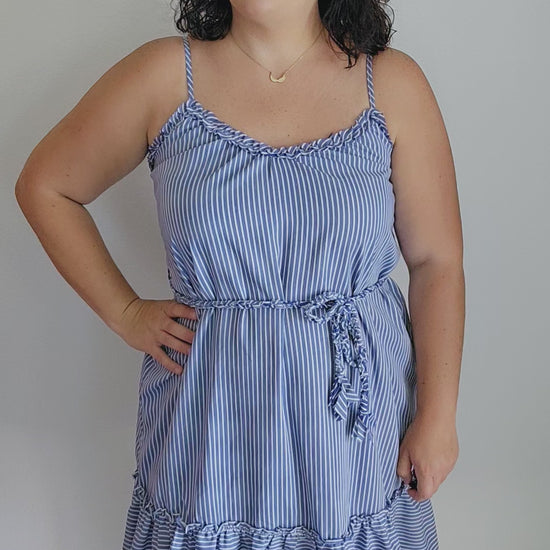 Get ready for some serious beach vibes with this gorgeous dress. This dress features a playful ruffle trim and hem, adjustable spaghetti straps for the perfect fit, and a braided belt for a touch of uniqueness. The vertical royal blue and white stripes will have you feeling like a seaside goddess. Sizes small through large.