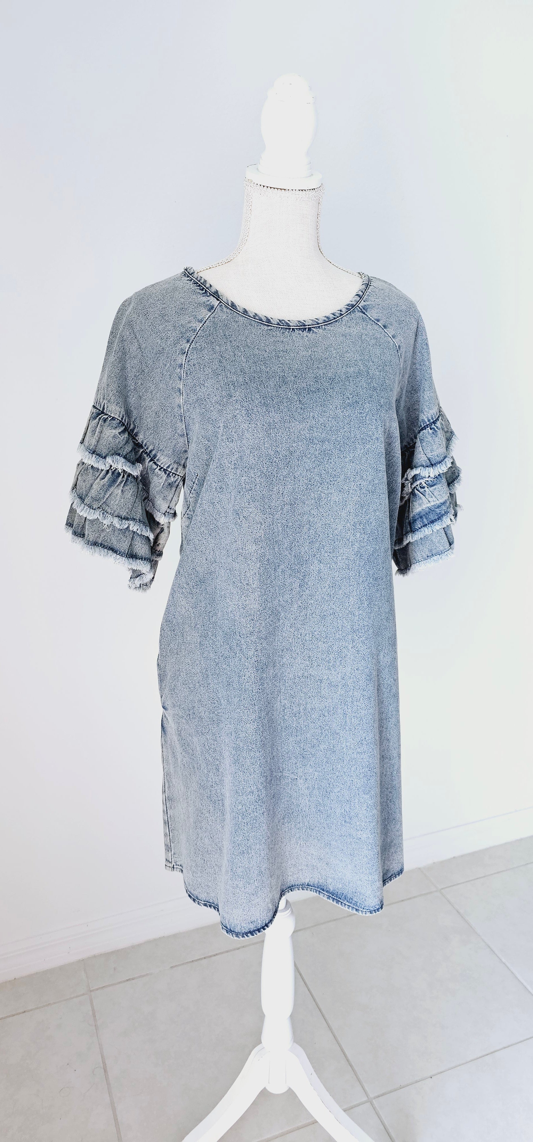 This light color denim dress features layered, short sleeves which have ruffles that are fringed/frayed, and comes above the knee. It has two functional pockets. Just slip it on over your head and you are ready to go! Go ahead and strut your stuff! This dress is great for a date, going to the office, or hanging out with the girls. Change the look of your dress by wearing different style belts as an added feature. Sizes small through large.