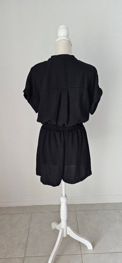 Step out in style in this black button down romper! Its lightweight fabric and classic V-neckline make it perfect for any occasion. And with its folded sleeves, high waist, elastic band, waist tie, and chest pocket, it's both chic and functional. It has two functional side pockets. A day or night look in one! Sizes small through large.