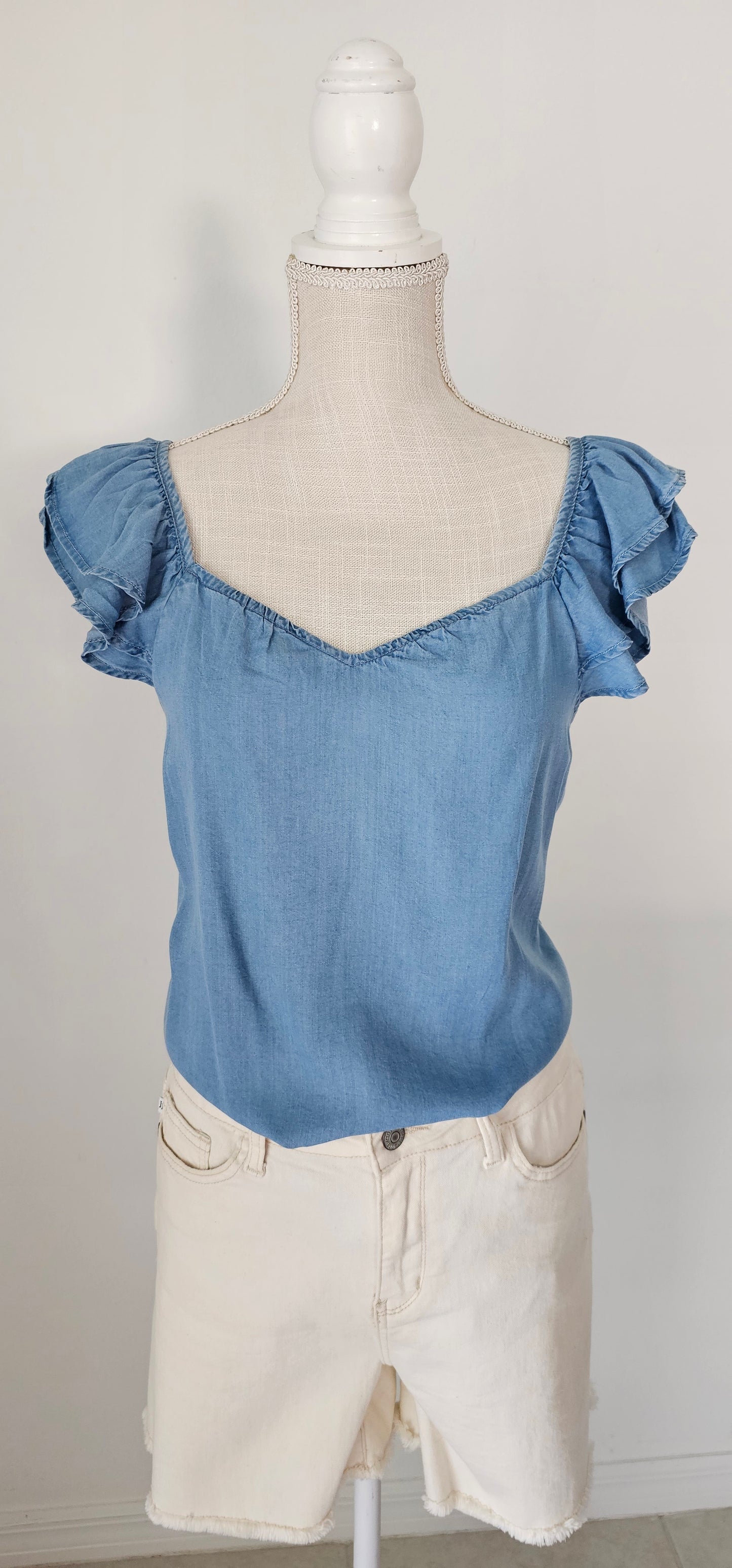 Look sharp and stylish this summer in our "Ashley Chambray Denim" top! Its flattering sweetheart neckline and sassy ruffle sleeves give you a unique, standout look. Plus, the square back neckline with elastic adds comfort! So why wait? Get out there and show off your denim 'look' with attitude. Sizes small through large.