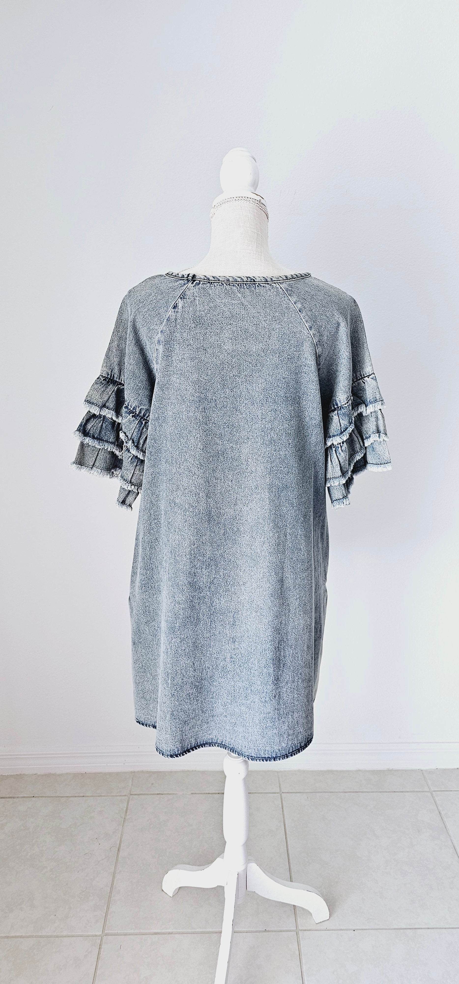 This light color denim dress features layered, short sleeves which have ruffles that are fringed/frayed, and comes above the knee. It has two functional pockets. Just slip it on over your head and you are ready to go! Go ahead and strut your stuff! This dress is great for a date, going to the office, or hanging out with the girls. Change the look of your dress by wearing different style belts as an added feature. Sizes small through large.