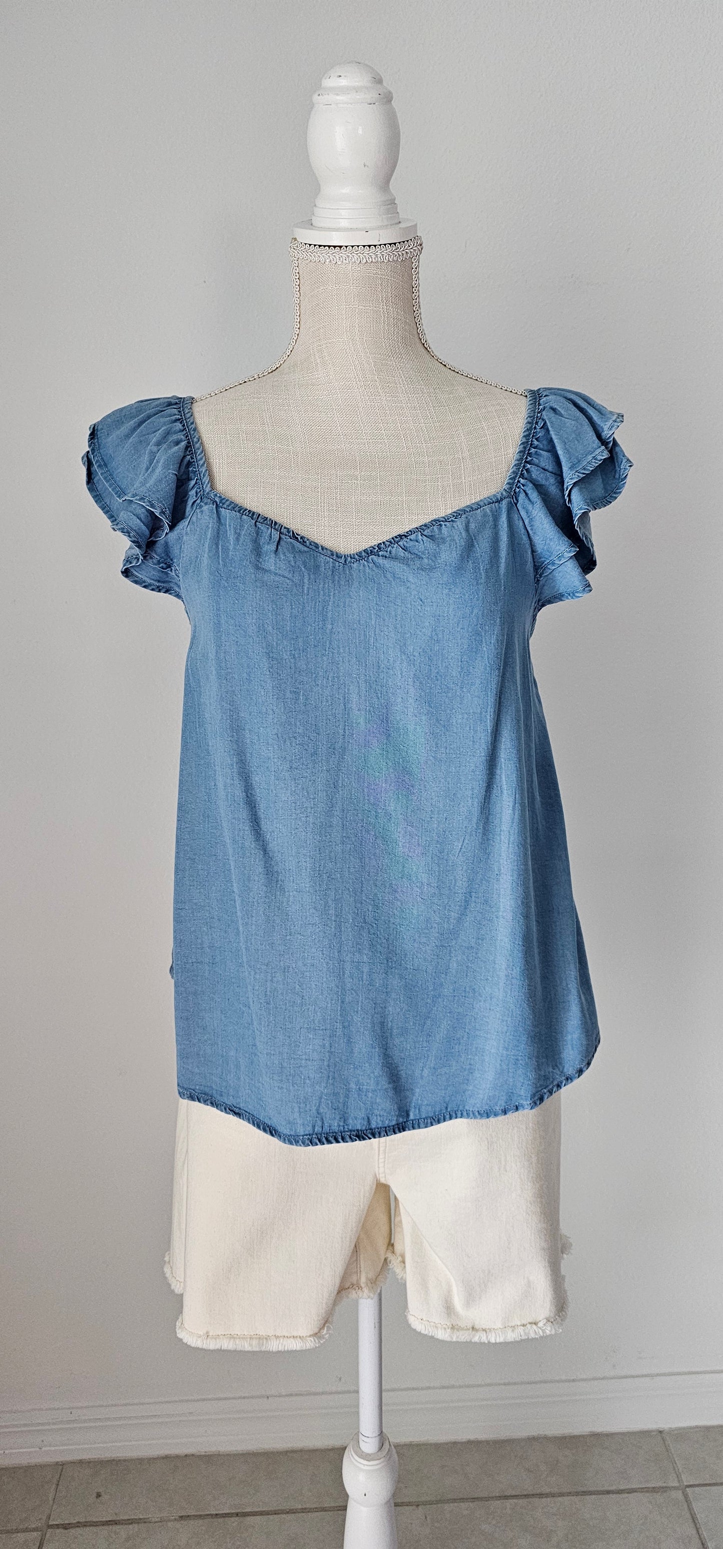 Look sharp and stylish this summer in our "Ashley Chambray Denim" top! Its flattering sweetheart neckline and sassy ruffle sleeves give you a unique, standout look. Plus, the square back neckline with elastic adds comfort! So why wait? Get out there and show off your denim 'look' with attitude. Sizes small through large.