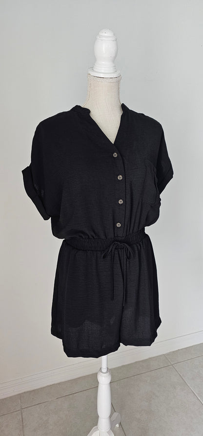 Step out in style in this black button down romper! Its lightweight fabric and classic V-neckline make it perfect for any occasion. And with its folded sleeves, high waist, elastic band, waist tie, and chest pocket, it's both chic and functional. It has two functional side pockets. A day or night look in one! Sizes small through large.