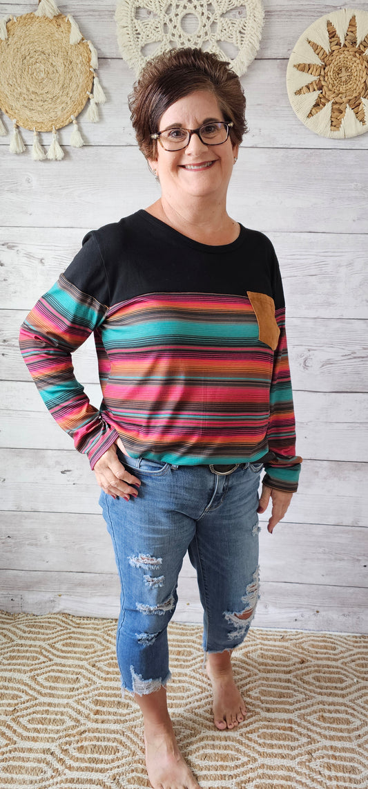 This top features a faux leather pocket, stripped sleeves, front and back. This long sleeve shirt screams Arizona! Get your cowgirl boots on and ride into town! Sizes small through x-large.