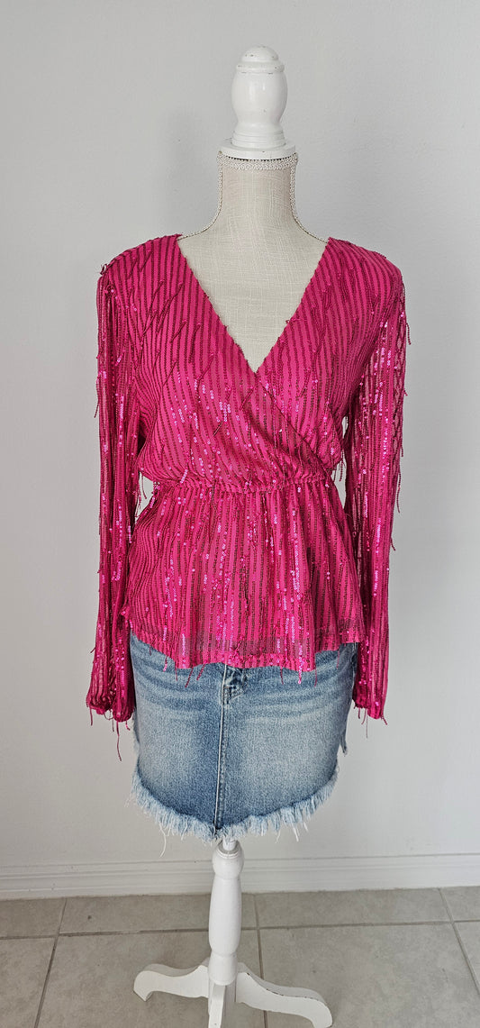 Add a touch of class to your casual outfit with this sequined top. The fringes add the perfect amount of edge without being too much for your everyday look! Peplum cut, surplice neckline, long puff sleeves. Sizes small through large.