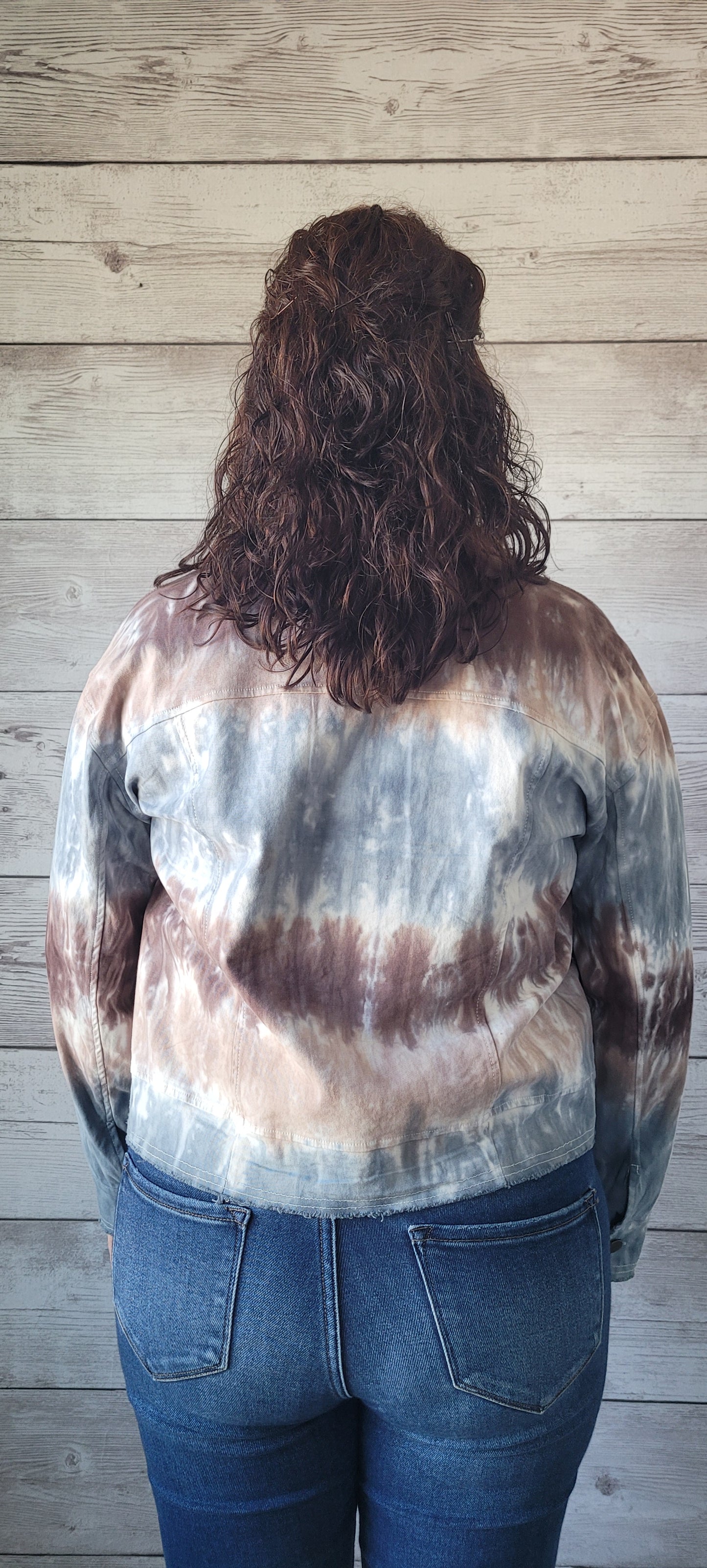 Make a statement with this adorable blue & brown tie dye trucker jacket! Enjoy the unique style of this timeless piece featuring metal button closure, bust flap pockets, and distressed hem and cuff edges. Wearing this piece is sure to cause a stir; try it and let the compliments roll in! Sizes small through large.