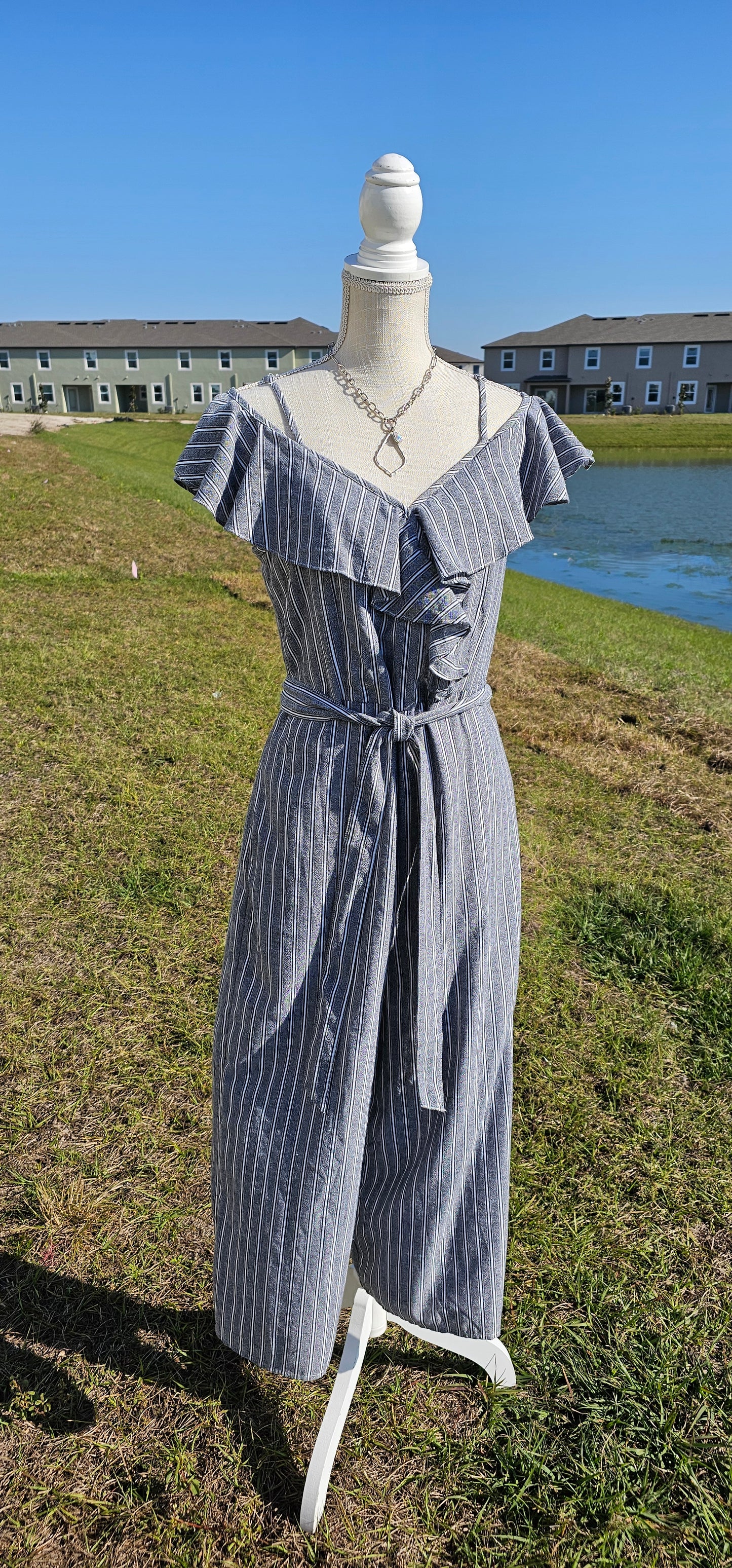 How adorable is the “Cool Breeze” jumpsuit. This jumpsuit features spaghetti straps that are adjustable, ruffled cold shoulder sleeves, ruffles down front in shape of a v, material tie belt for around waist, wide cropped legs, the pants have pockets, zipper and eyelet hook in back, and has gray, white, and black stripes. Just slip it on and you are ready for the day!&nbsp; I hear that a vacation is planned.&nbsp; What a great item to pack in your suitcase. Sizes small through large.