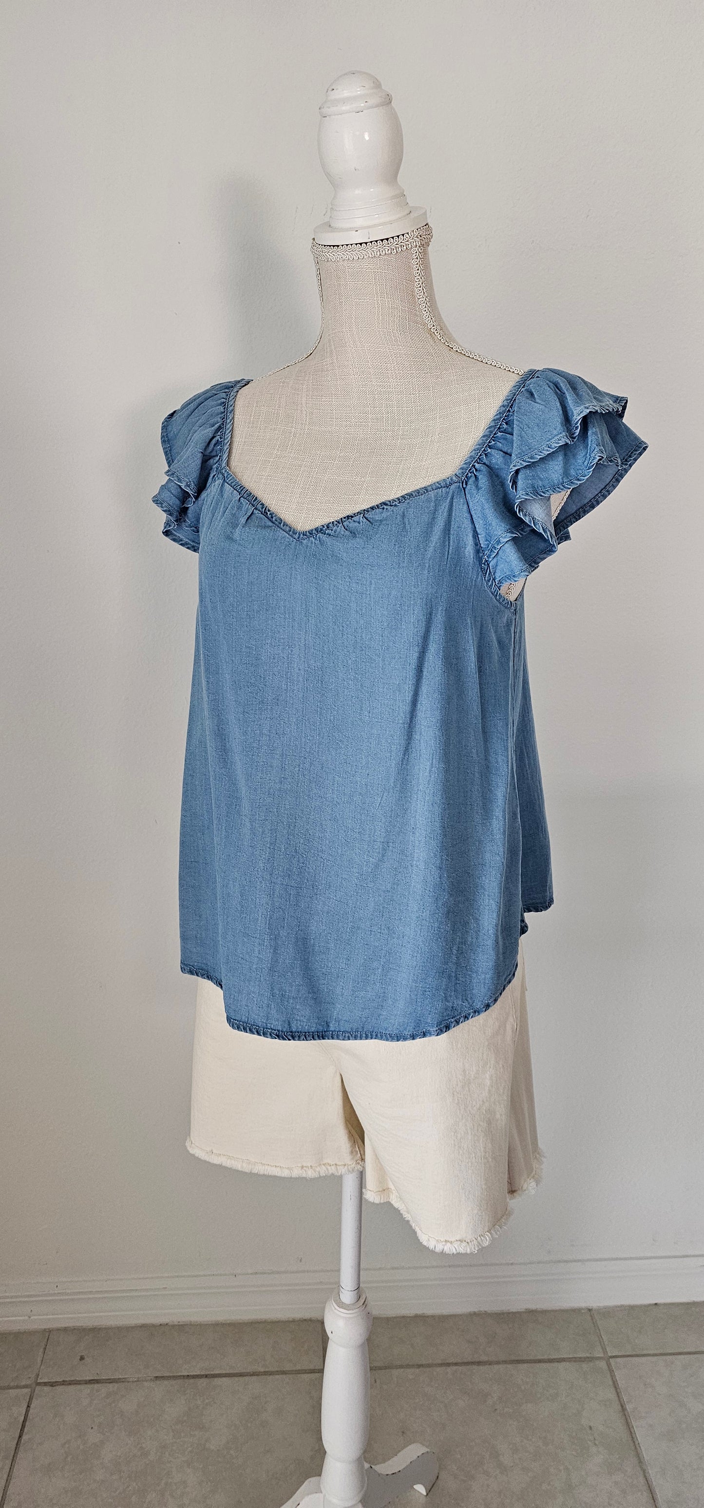 Look sharp and stylish this summer in our "Ashley Chambray Denim" top! Its flattering sweetheart neckline and sassy ruffle sleeves give you a unique, standout look. Plus, the square back neckline with elastic adds comfort! So why wait? Get out there and show off your denim 'look' with attitude. Sizes small through large.