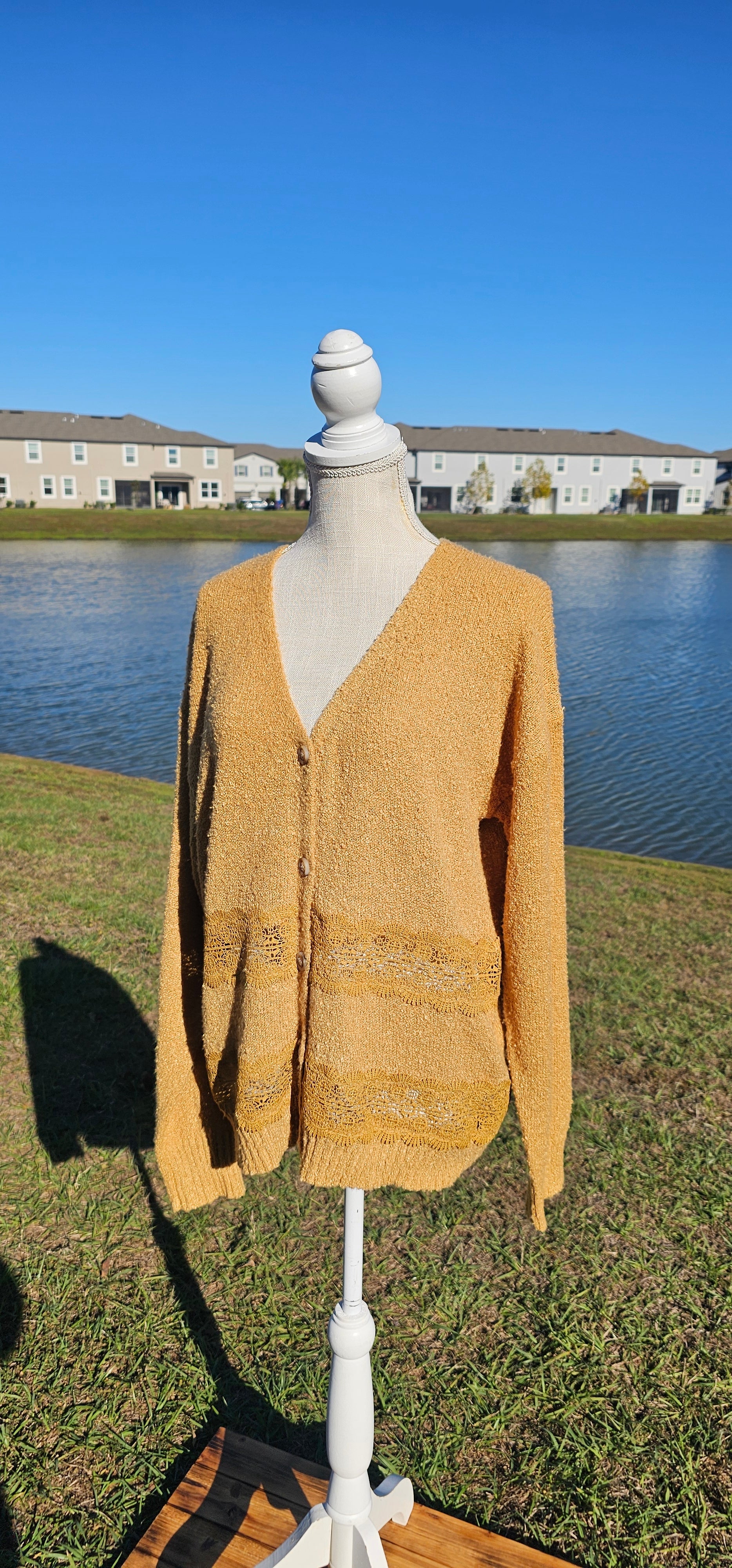 Lightweight mustard cardigan features a button down front, crotchet lace trim detailing, and a classic v-neck. Sizes small-large.