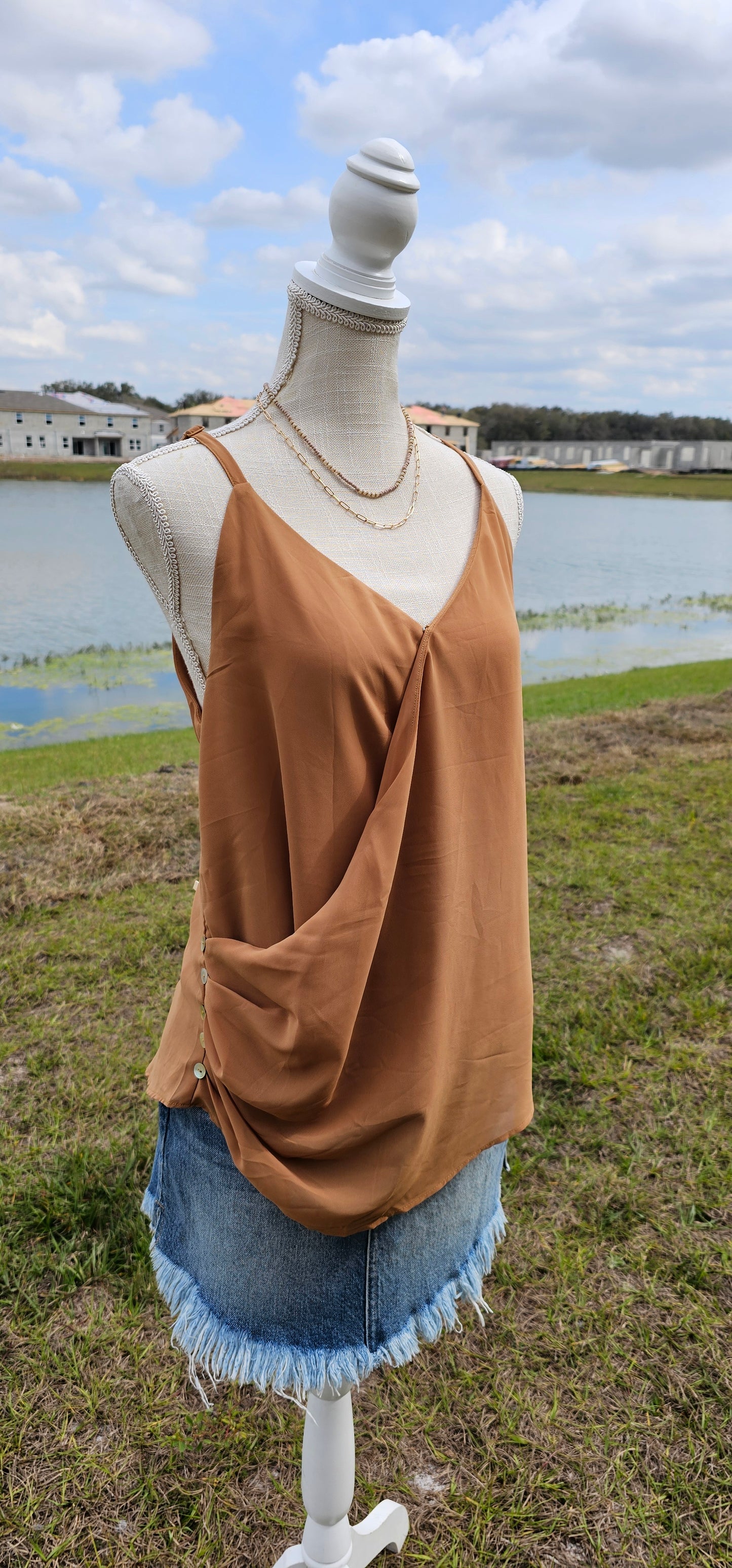 “Frappuccino” is a woven double layer chiffon top, featuring buttons up the side, surplice neckline, and adjustable spaghetti straps. This top is perfect for layering or great all by itself. Sizes small through x-large.