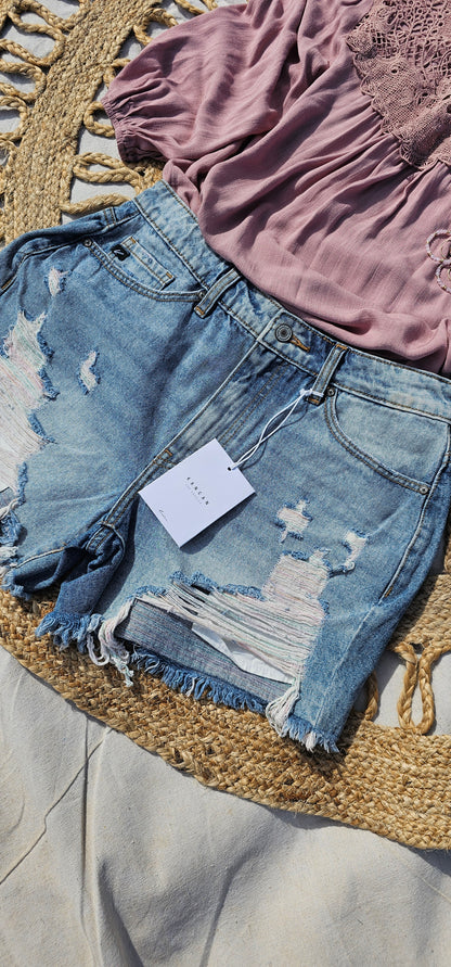 These denim distressed shorts are a light wash, high rise, frayed hem with hues of pink and blue. They are cute, edgy and scream summer vibes! Sizes small through x-large.