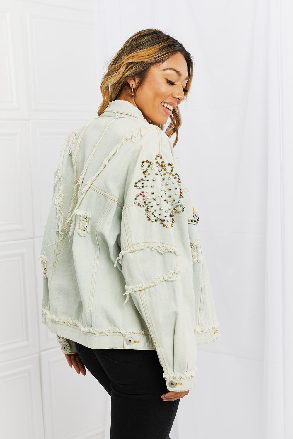 You will definitely turn head with this timeless denim jacket. This relaxed fit jacket features button front closures, distressed detailing and colorful pearl beaded details along the sleeves and front pockets. Pair with a dress or pants for an elevated casual look.