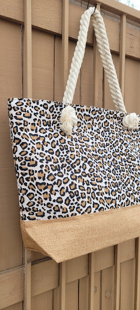 This leopard print tote features a cream color braided handle with a zipper top.&nbsp; The material is polyester. The inside has a lining with a pocket for all of the small stuff that you do not want to get lost.&nbsp; The outside bottom has a burlap color fabric. This tote is very versatile.&nbsp; Imagine yourself heading to the beach, going shopping, or heading to the local market, you will get a lot of use out of this super cute tote.