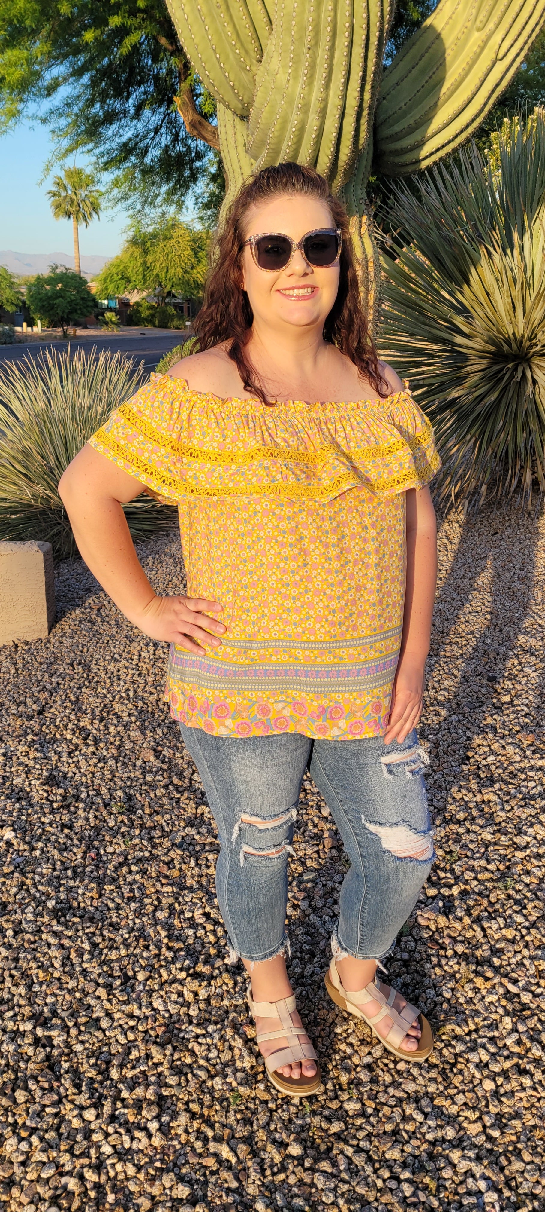 “Sunshine On My Shoulders” is an off the shoulder smock top. This top features a ray of subdued colors (dandelion yellow, mauve, ceil blue, white), elastic ruffled neckline, and crochet lace design. This top is a longer length, it does not have stretch, and is super lightweight and breathable. Sizes small through large.