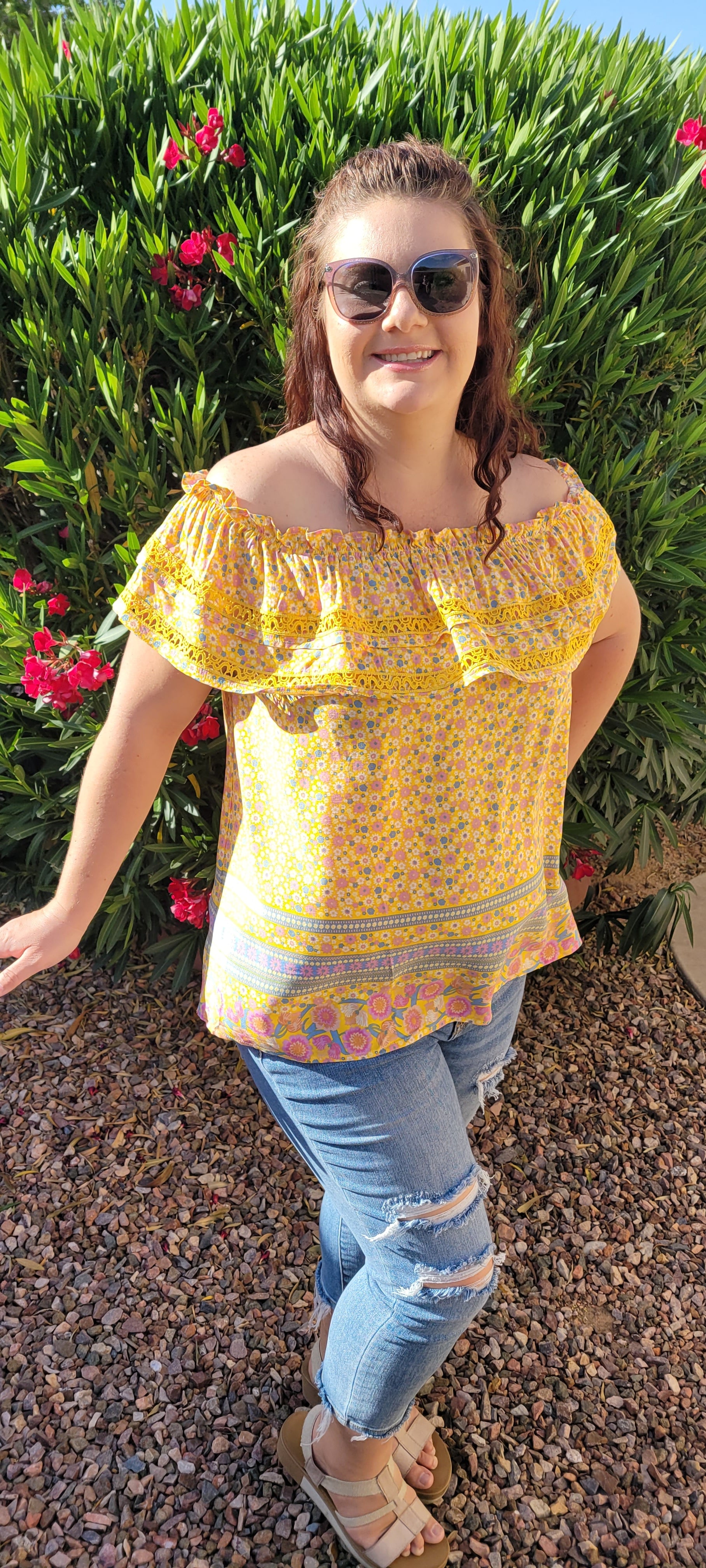 “Sunshine On My Shoulders” is an off the shoulder smock top. This top features a ray of subdued colors (dandelion yellow, mauve, ceil blue, white), elastic ruffled neckline, and crochet lace design. This top is a longer length, it does not have stretch, and is super lightweight and breathable. Sizes small through large.