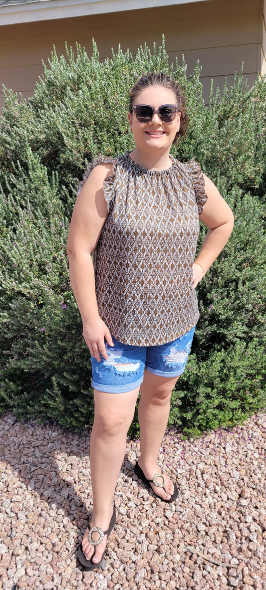“Pretty Penny” is a patterned sleeveless blouse featuring a rounded hemline, a ruffled elastic neckline and ruffled sleeves. It is a waffle knit, relaxed fit. This is unlined, non-sheer, and lightweight. The colors are camel, white and black. Sizes small, medium and large