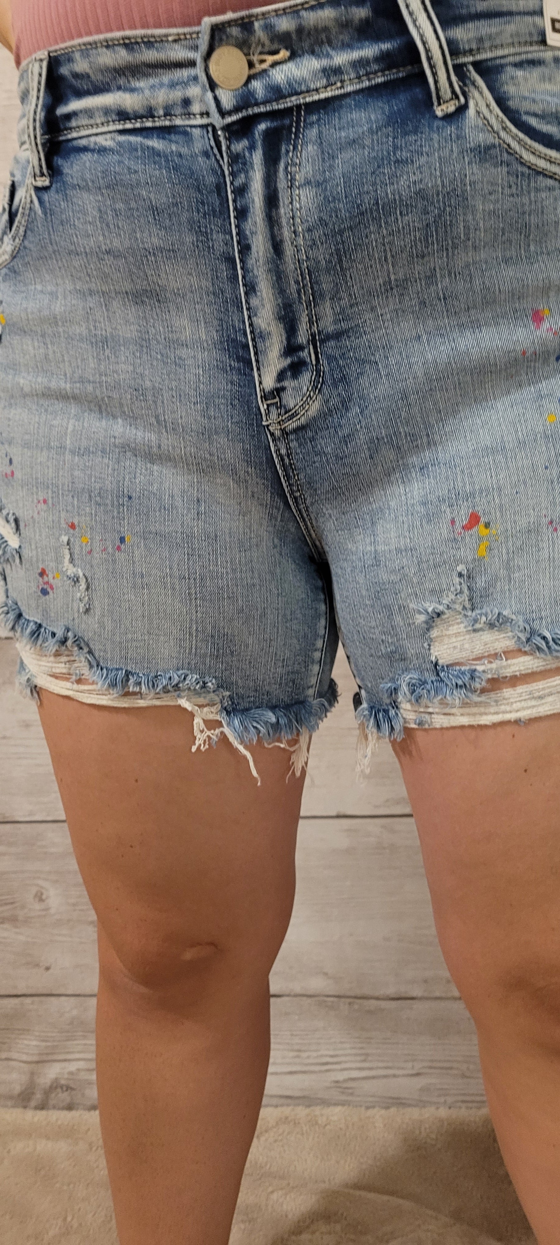 These are mid rise, light wash, distressed shorts featuring paint splatter (blue, yellow, pink), a frayed and distressed hemline, functional pockets in the front and back.  These shorts are stretchy for comfort. Sizes small through x-large.