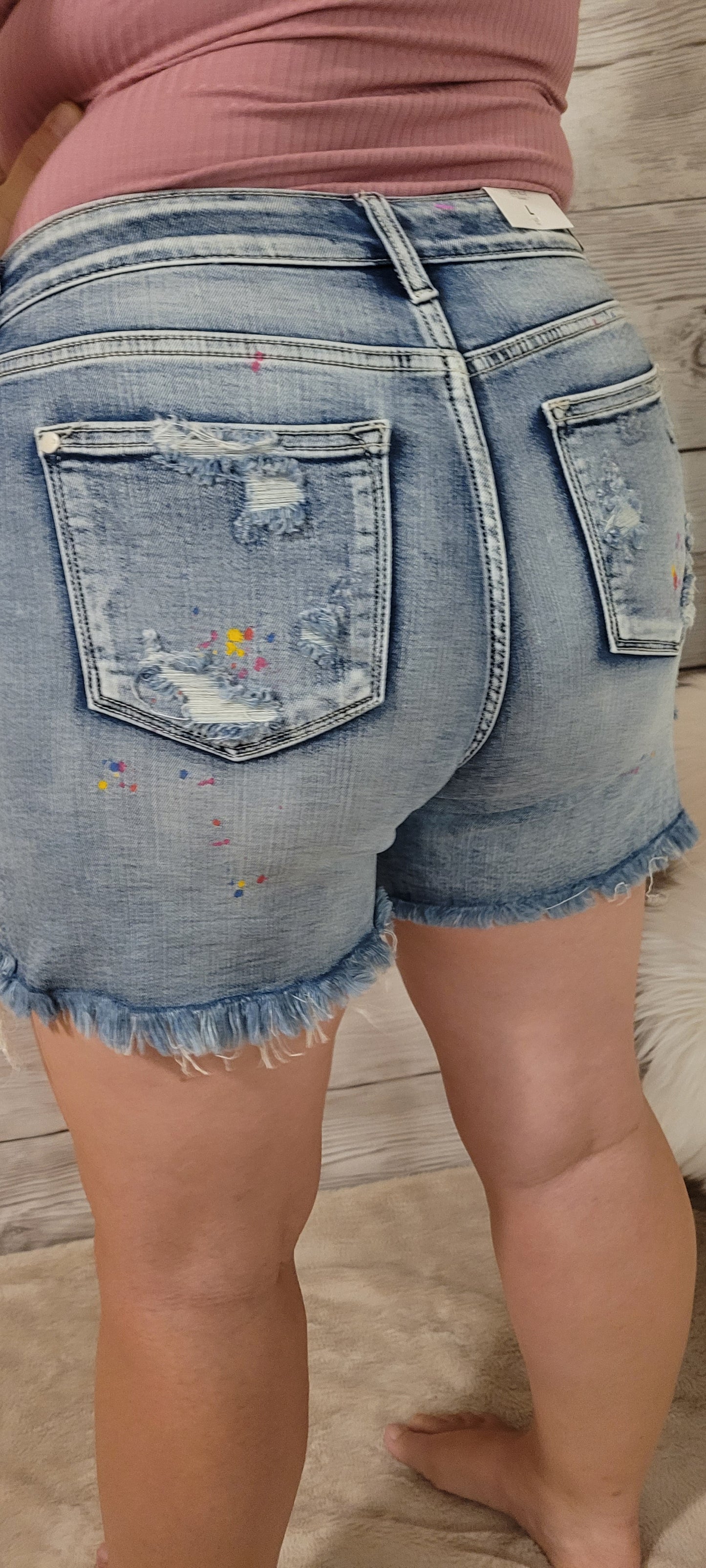These are mid rise, light wash, distressed shorts featuring paint splatter (blue, yellow, pink), a frayed and distressed hemline, functional pockets in the front and back.  These shorts are stretchy for comfort. Sizes small through x-large.