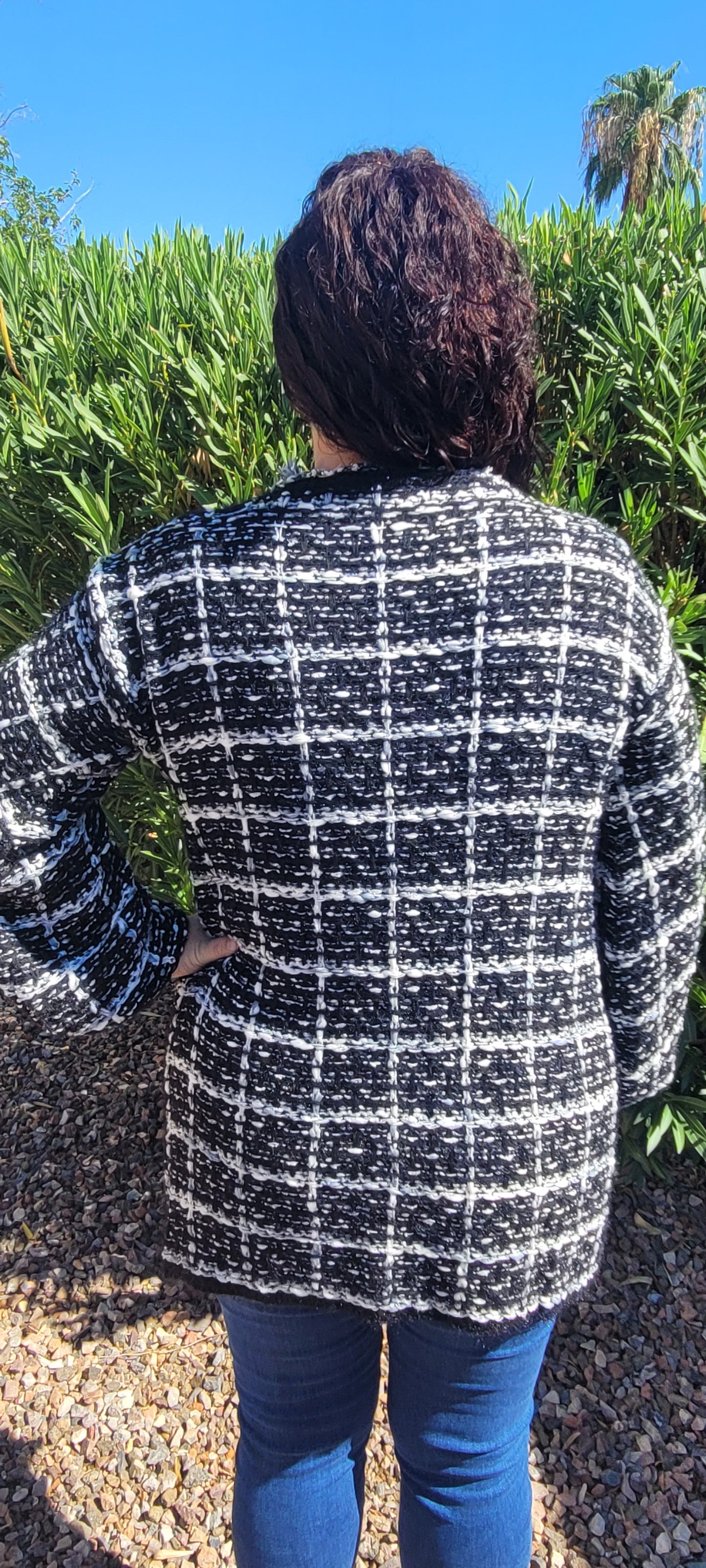 “Check Mate” is a loose cable knit cardigan sweater, which features an open front, an eyelet hook at the bust, two functional pockets that are open at the top, balloon sleeves with elastic cuffs, frayed trim on neckline and front. The colors are black, white, and gray. This sweater is so soft and comfy. This cute number can be used as a jacket or sweater. Sizes small through large.