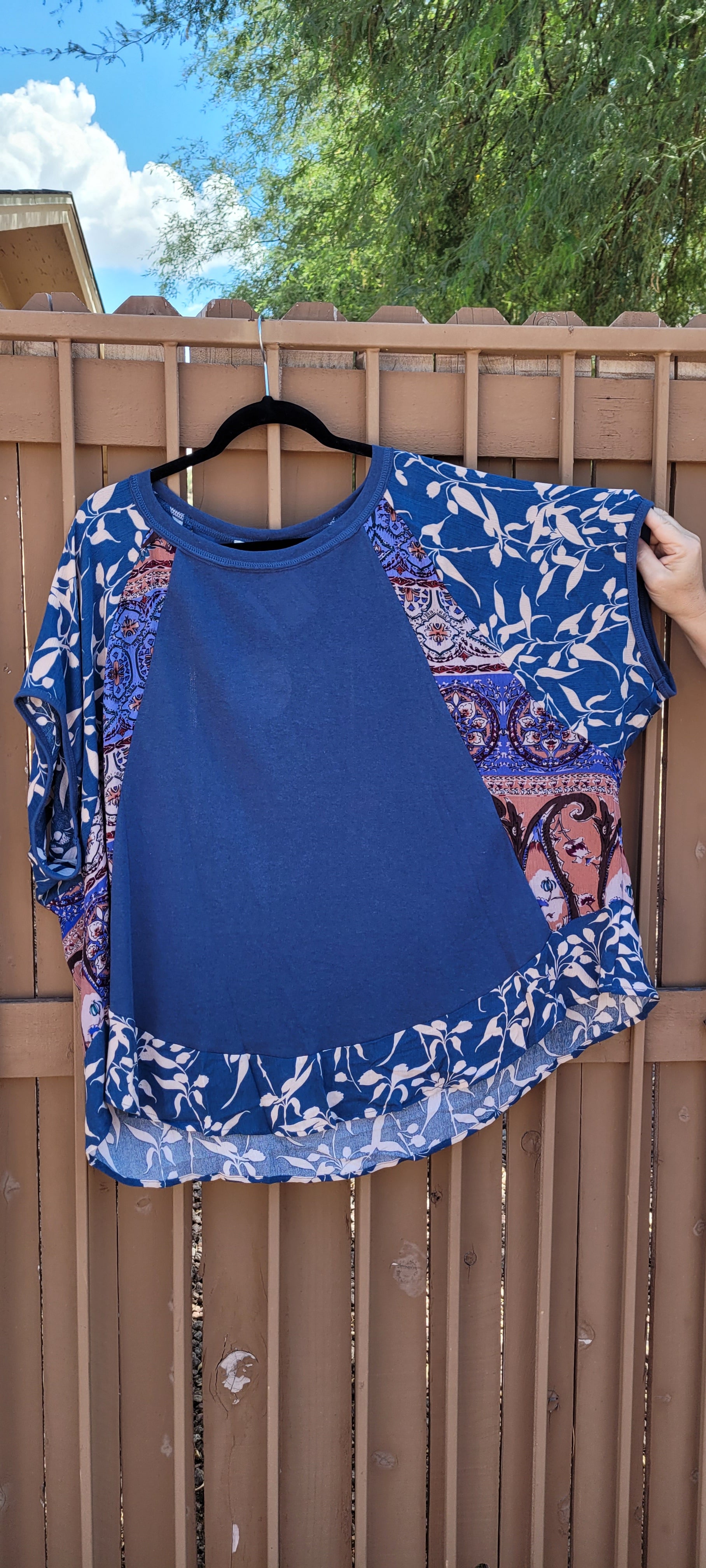 “I've Got The Blues” is a Egyptian blue blouse. This top features a scoop neckline, dolman sleeves, high low rounded hemline, trimmed with floral print on hemline and sleeves, layered floral pattern on back. This is a loose fitting top. It is perfect for the office setting. Size 2X-Large.
