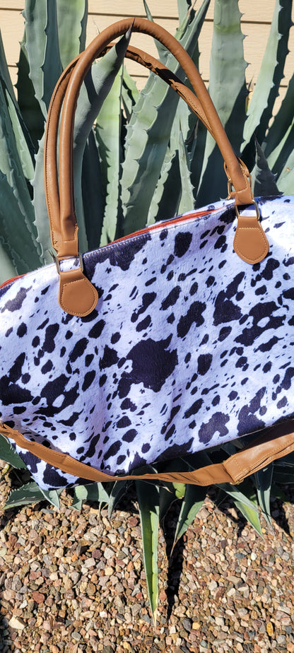 Cow Print Weekender Tote Bag Colors: white, black, camel Removable shoulder strap Carrying handles Zipper pouch Cellphone holder/side pockets Material is polyester Measurements: height: 12 inch, width: 25.5 inch, diameter: 8.5 inch and carrying handle height: 8 inch