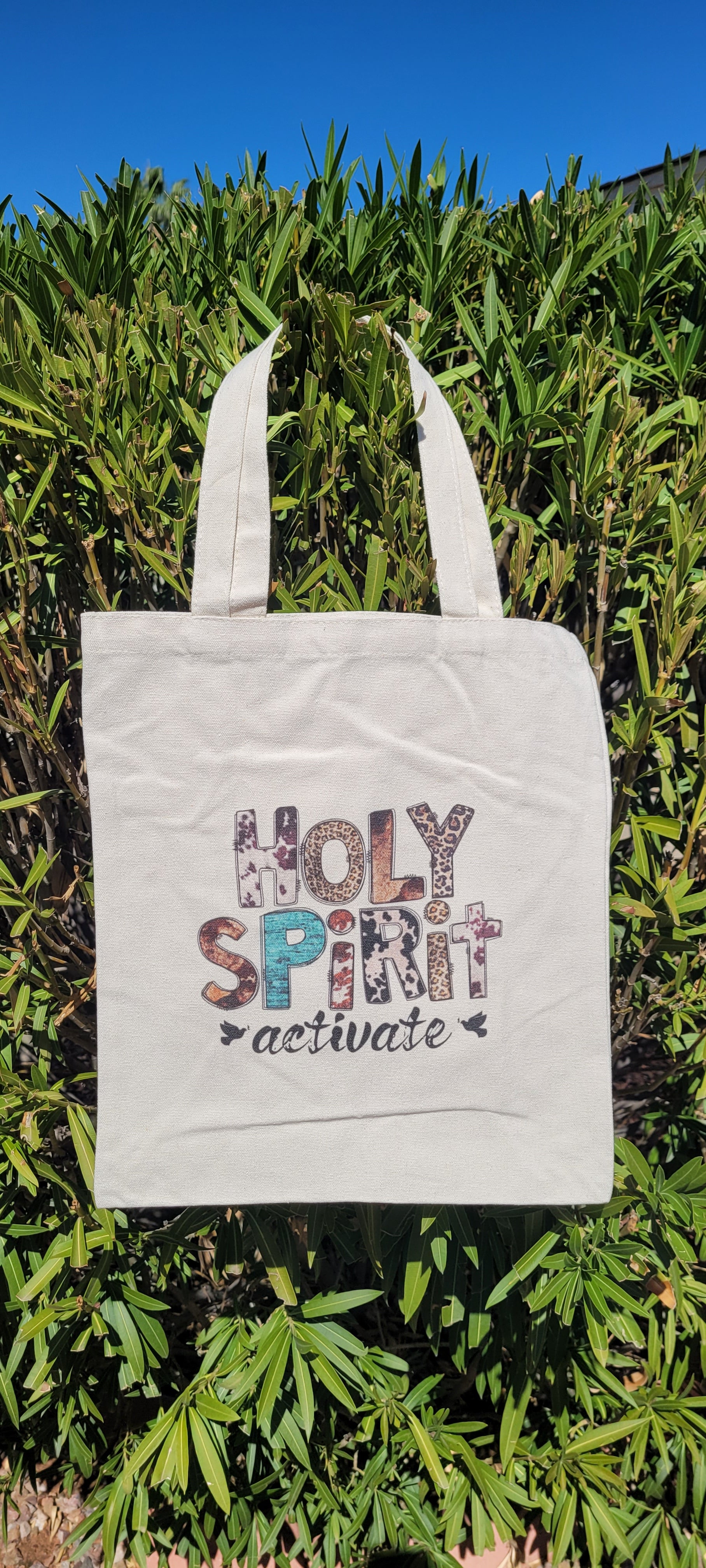 These trendy tote bags are a must have! Holy Spirit Activate lettering Cow print, leopard print, turquoise pattern Material is polyester Size is height: 15.25 inch, width: 13.5 inch, diameter: 0.125 inch and strap height: 8.5 inch