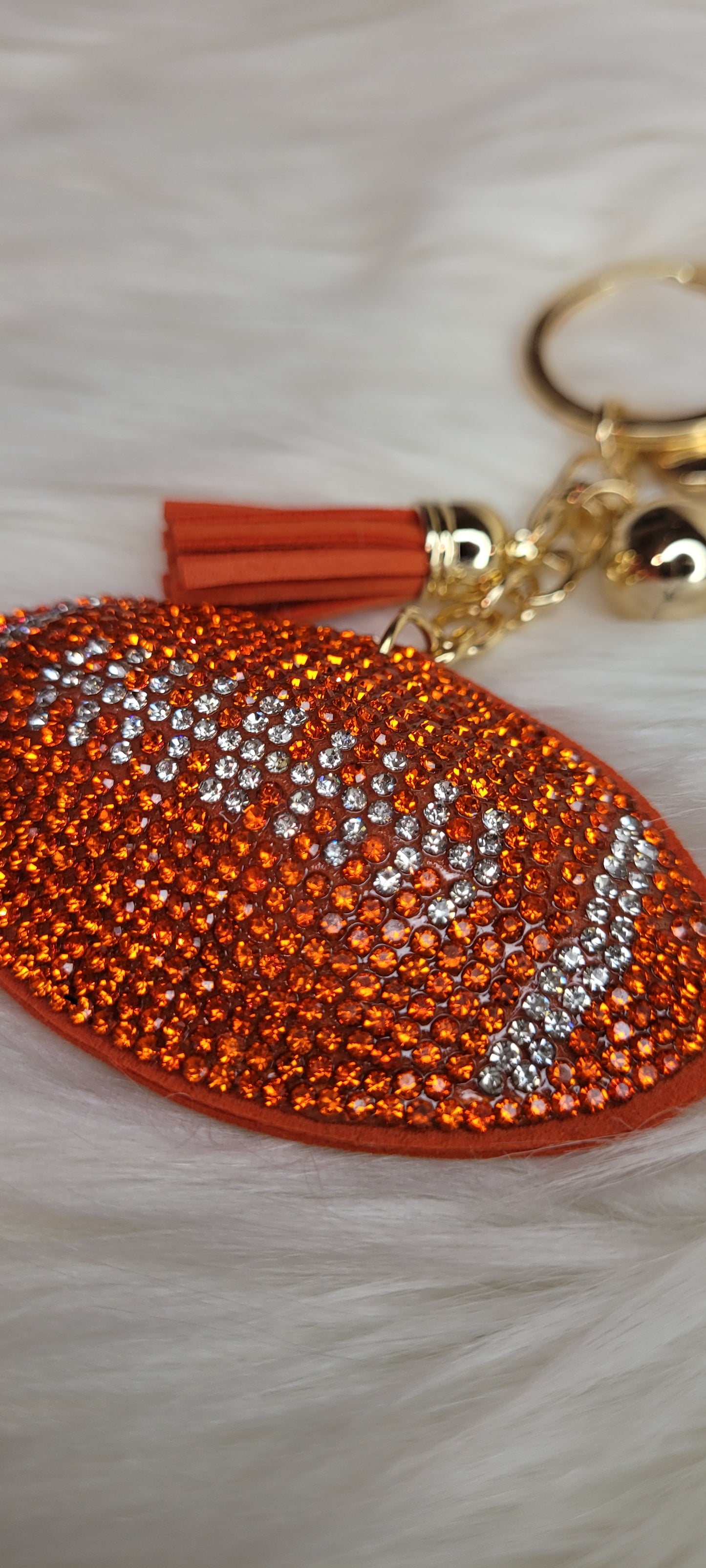 Football keychain Rhinestones are orange and clear in the shape of a football Faux leather backing and tassel Gold color chain, key ring and ball These key chains will not last long