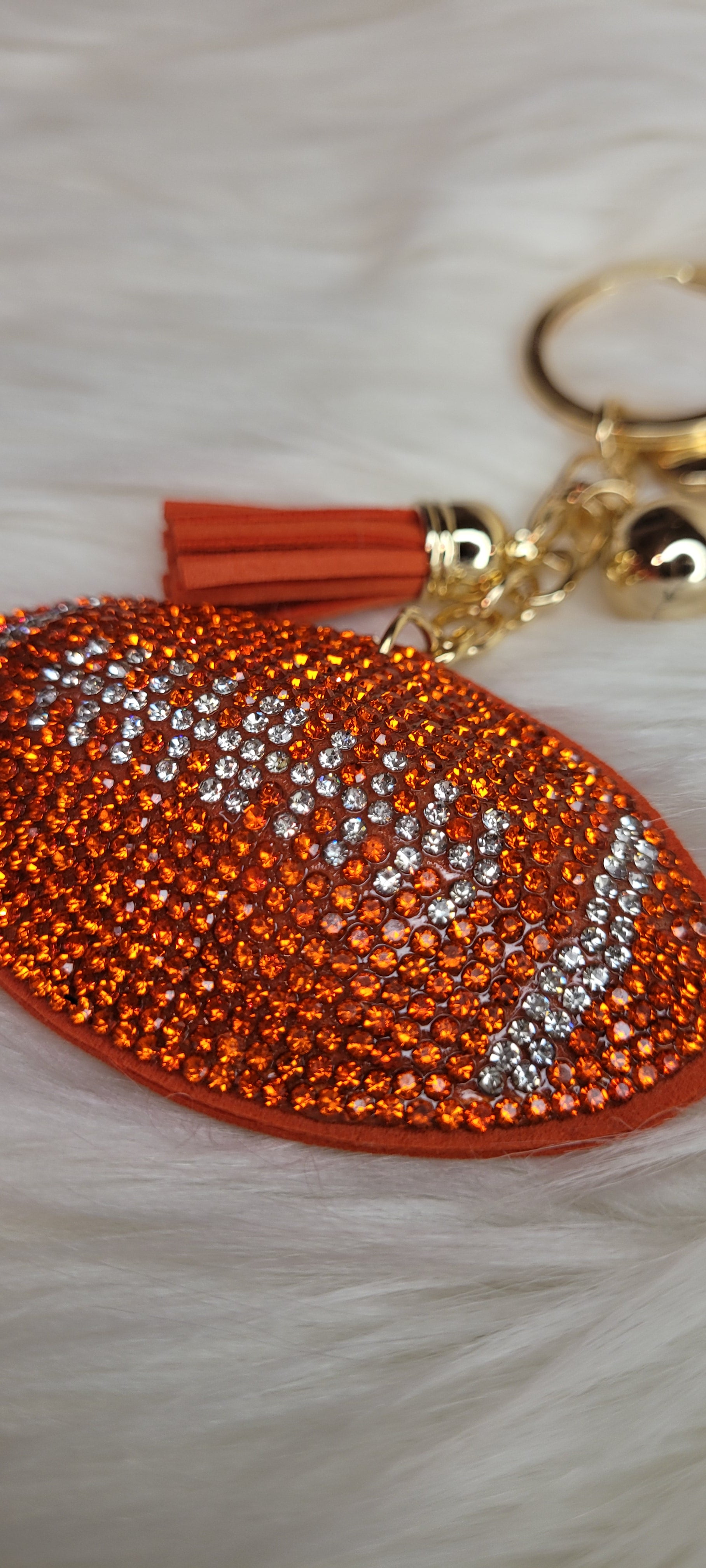 Football keychain Rhinestones are orange and clear in the shape of a football Faux leather backing and tassel Gold color chain, key ring and ball These key chains will not last long